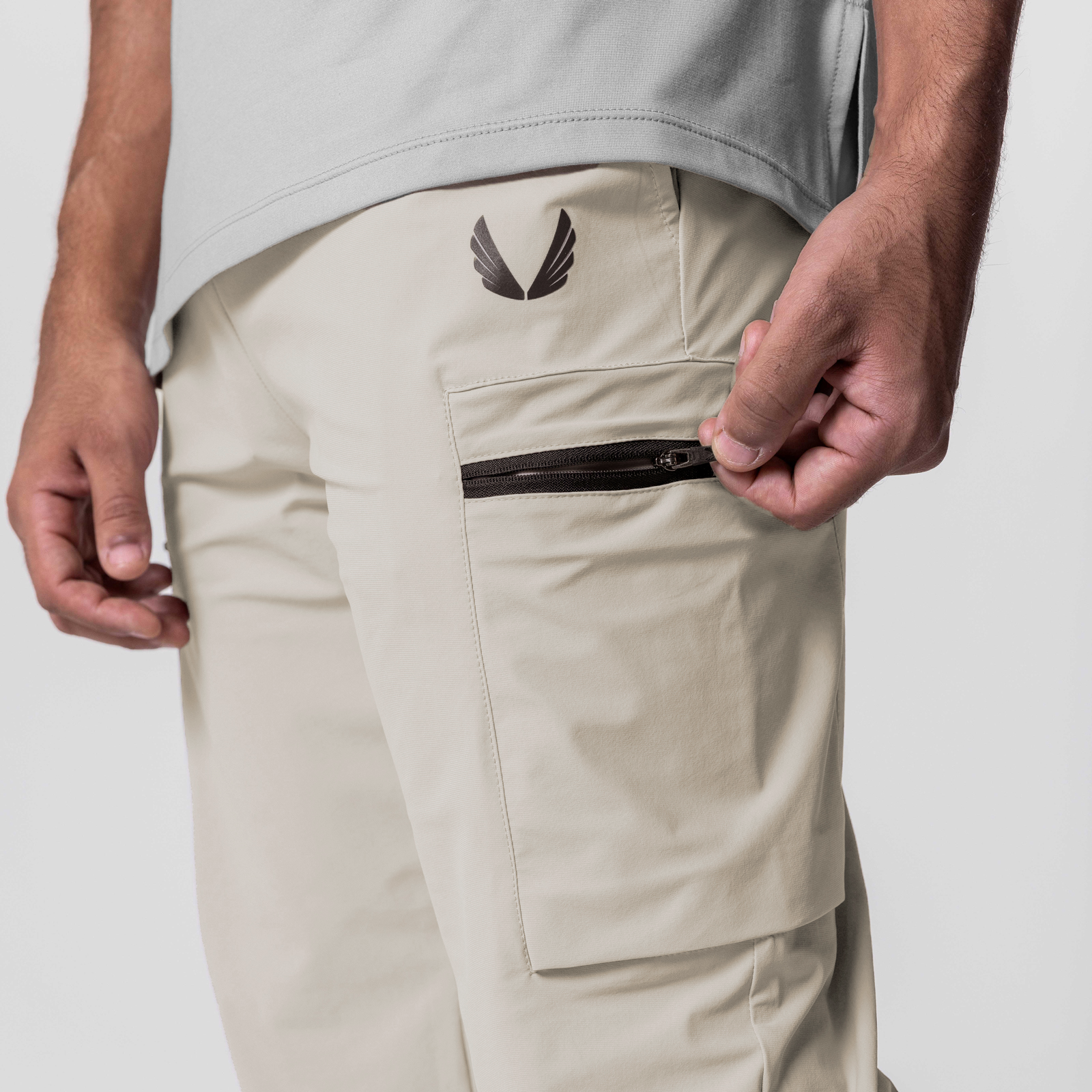 Tetra-Lite Standard Zip Jogger in sand, modeled with hands opening cargo pocket