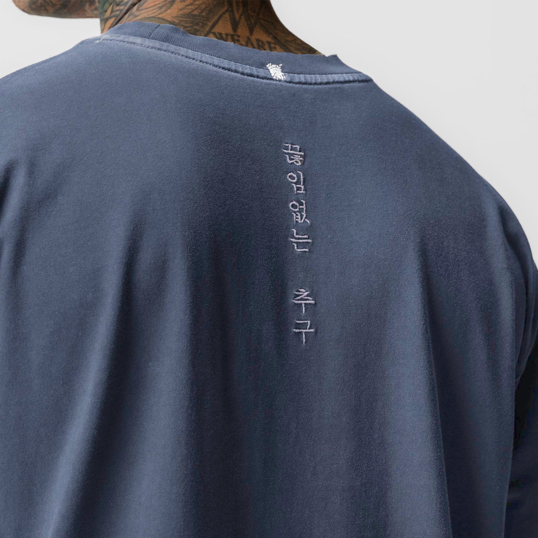 Tech Essential Relaxed Long Sleeve in faded navy worn by model, back view showing vertical text detail