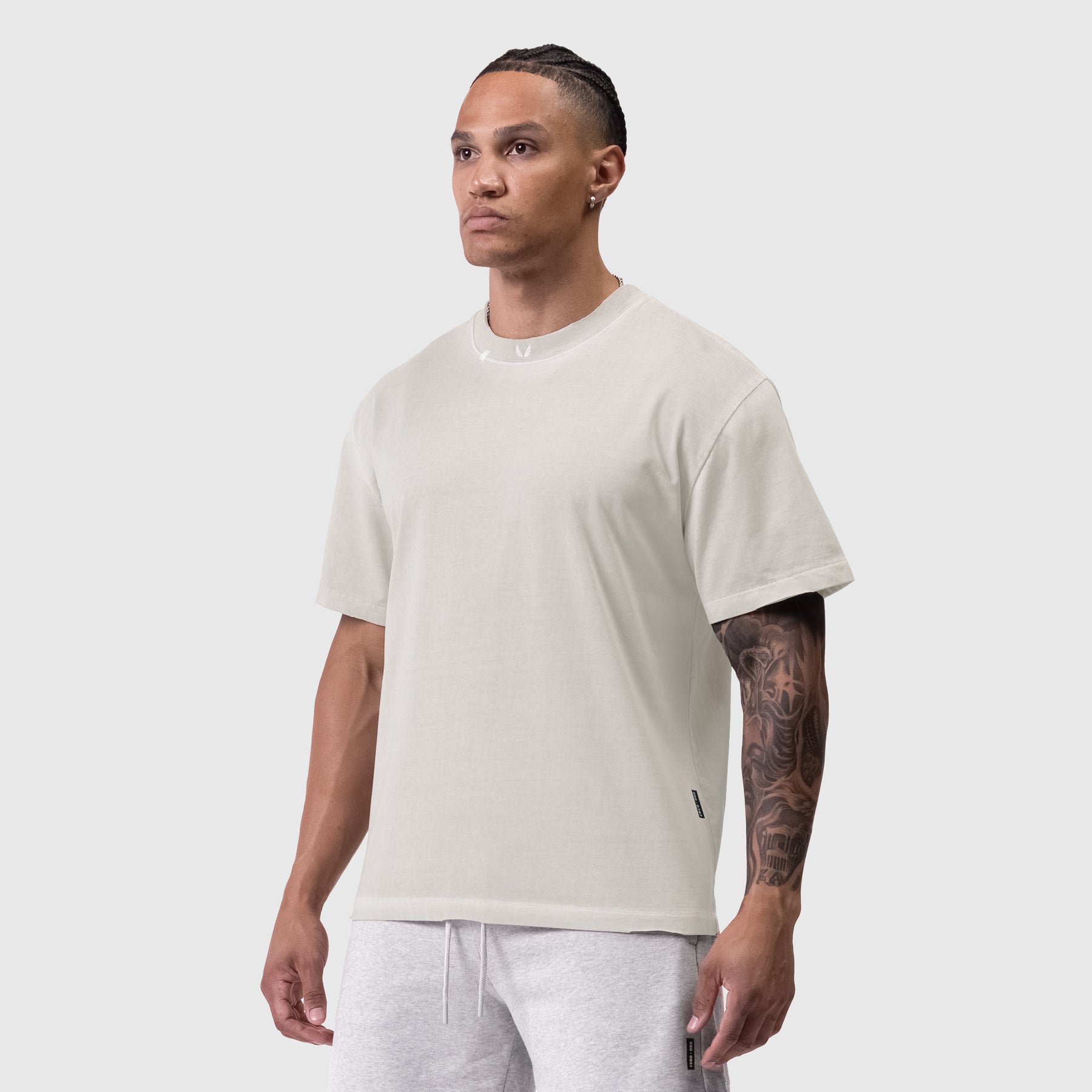 Tech Essential Relaxed Tee in faded stone, worn by model standing against neutral background