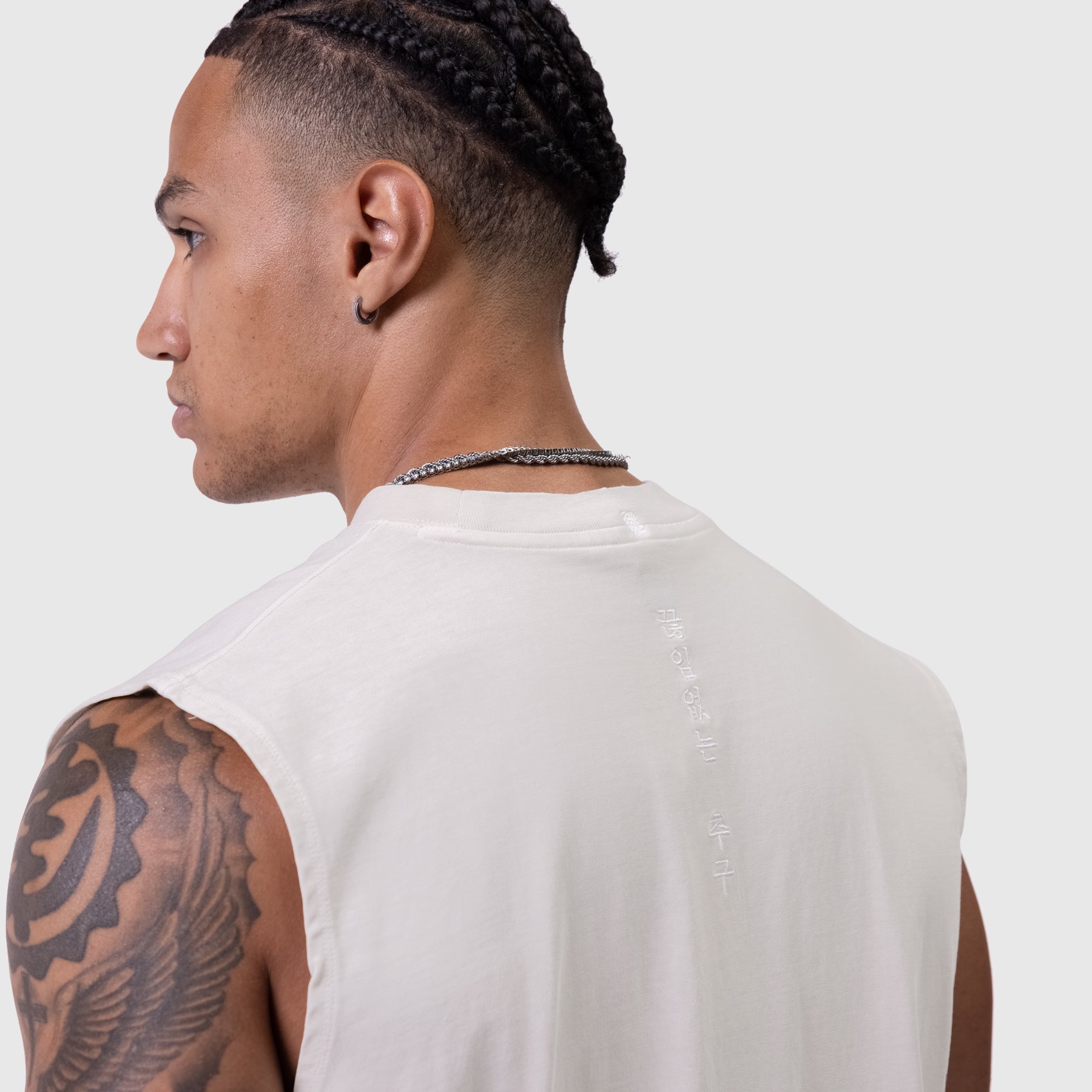 Tech Essential Relaxed Cutoff tank top in faded stone, worn by model showing back view