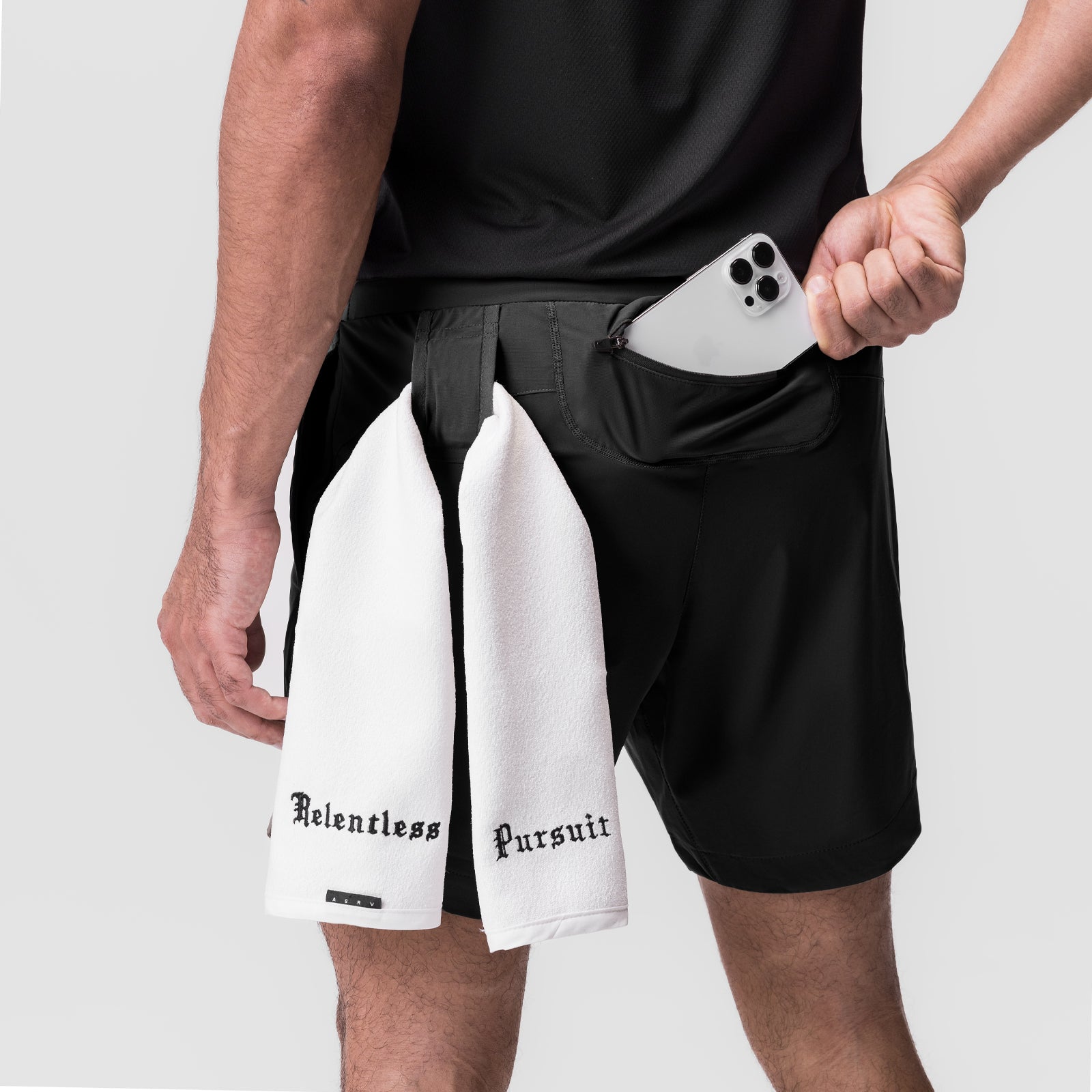 Black Tetra-Lite 7" Linerless Shorts worn by model holding white "Relentless Pursuit" towel