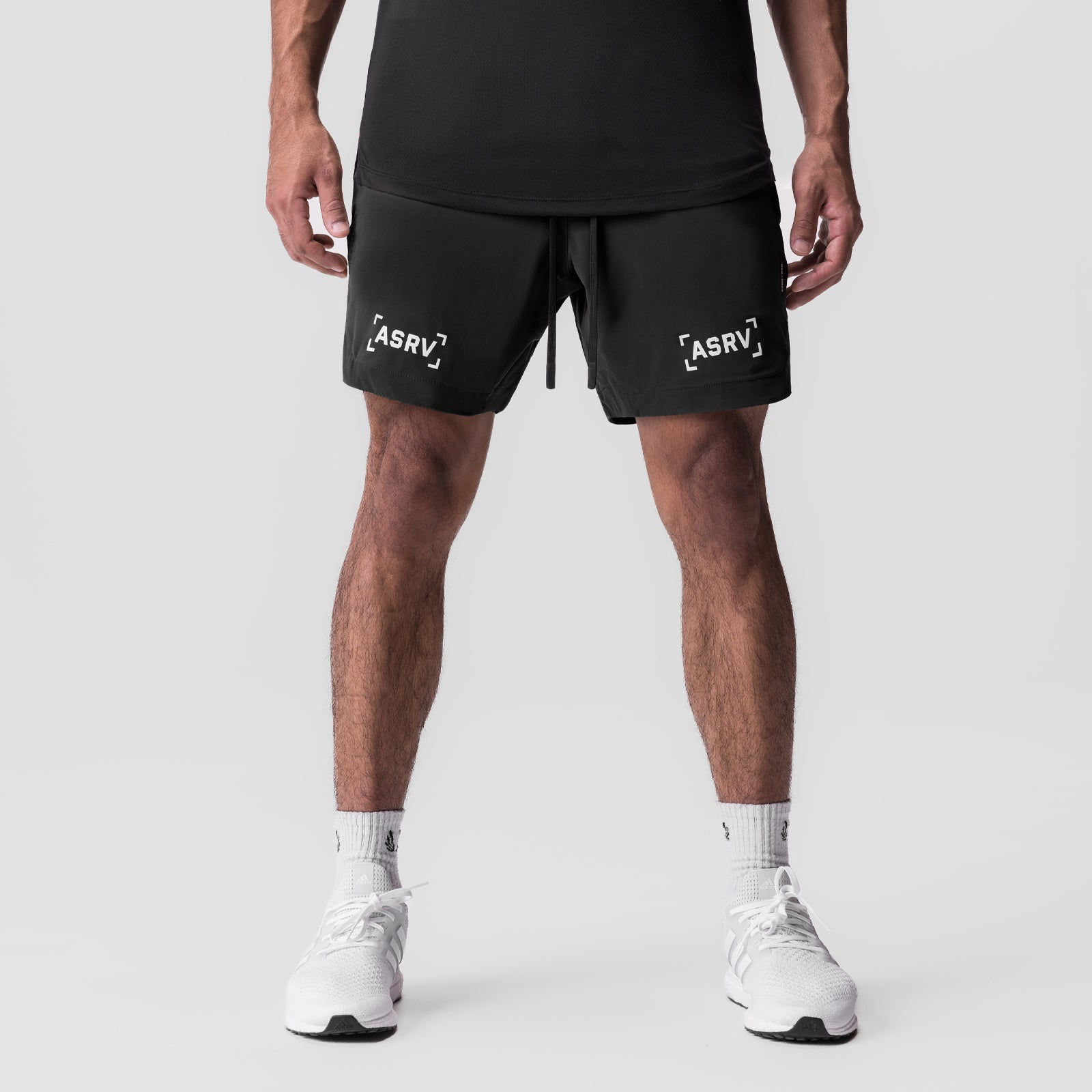 Black Tetra-Lite 7" linerless shorts with white bracket logo, modeled front view with white sneakers