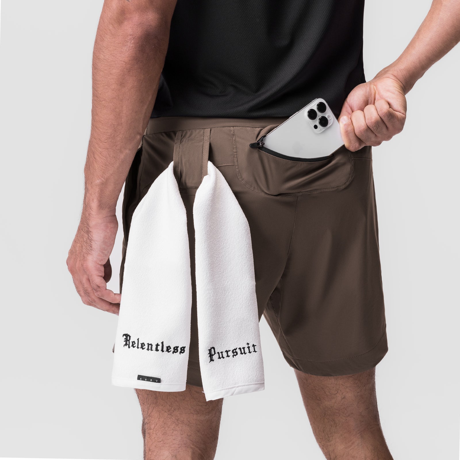 Tetra-Lite 7" Linerless Short in Deep Taupe worn with white towel, model holding phone in pocket