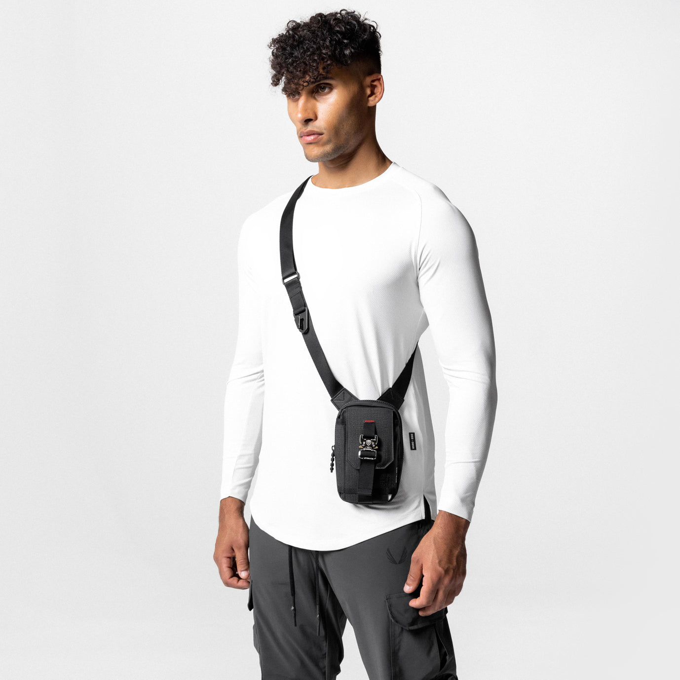 Waterproof phone holster bag in black, worn as crossbody sling on model in white long-sleeve shirt