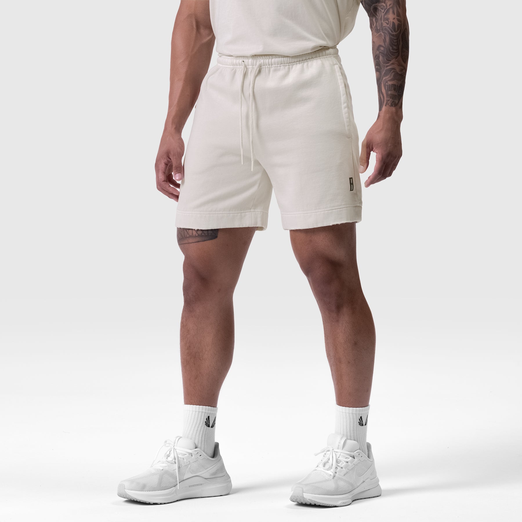 Tech Essential Sweat Short in faded stone, worn by model standing in neutral pose