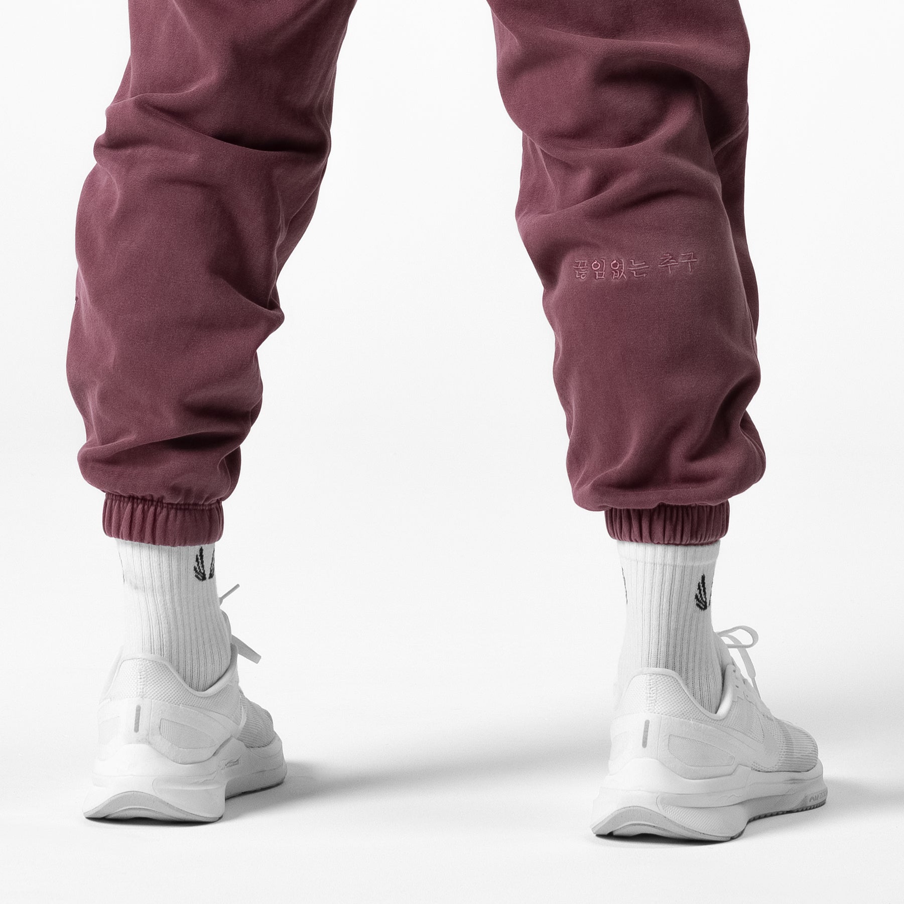 Tech Essential Sweats in faded crimson worn with white socks and sneakers, back view