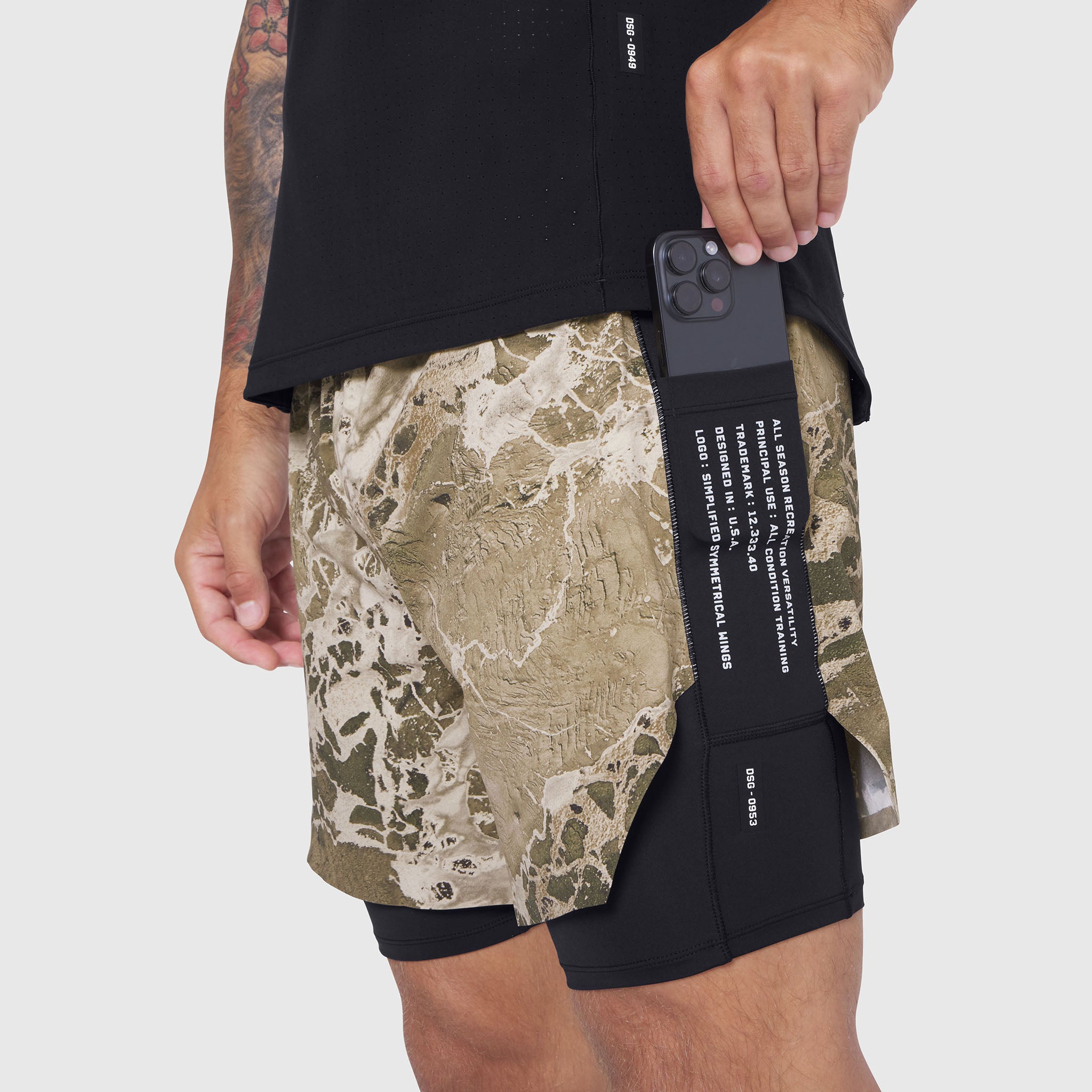 Aerotex Hybrid Liner Short in khaki Realtree camo with black liner, worn by model holding phone