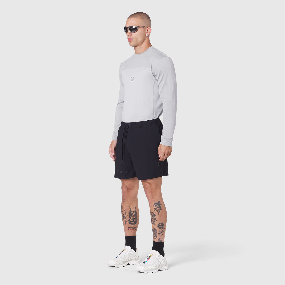 Revolutional Training Short in black, modeled with long-sleeve top and white sneakers, side view