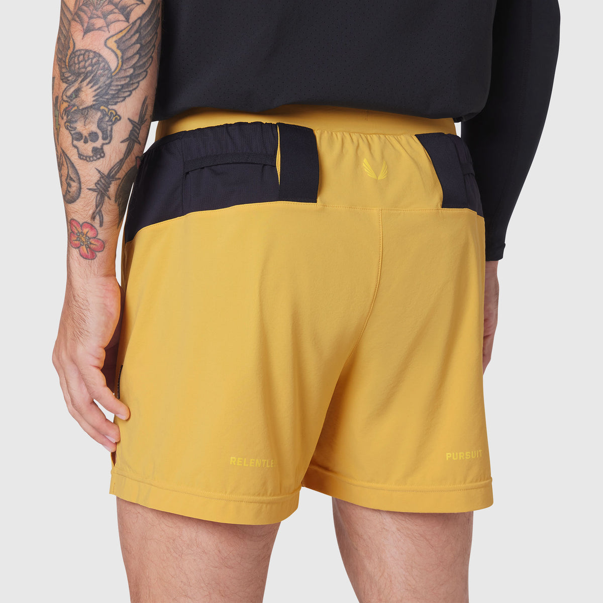 Aerotex Distance Run Short in amber yellow, back view on model with tattoos