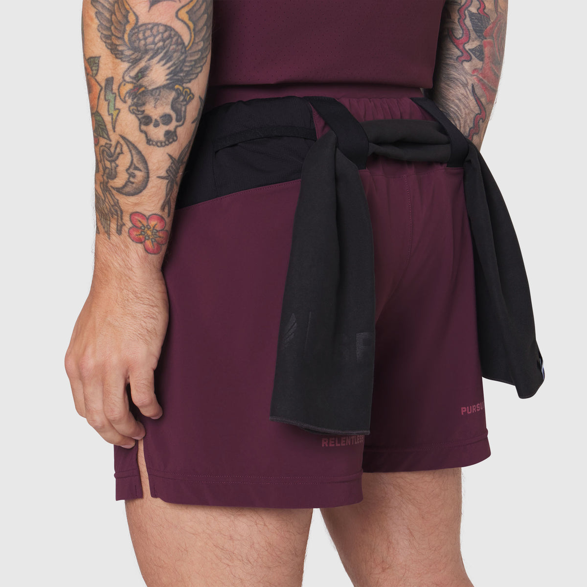 Aerotex Distance Run Short in merlot worn by model with black jacket tied at waist