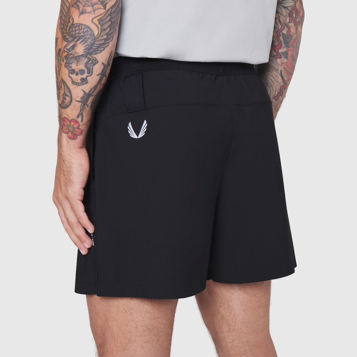 Black TETRA-LITE training shorts on model, side view showing 5" inseam and back pocket