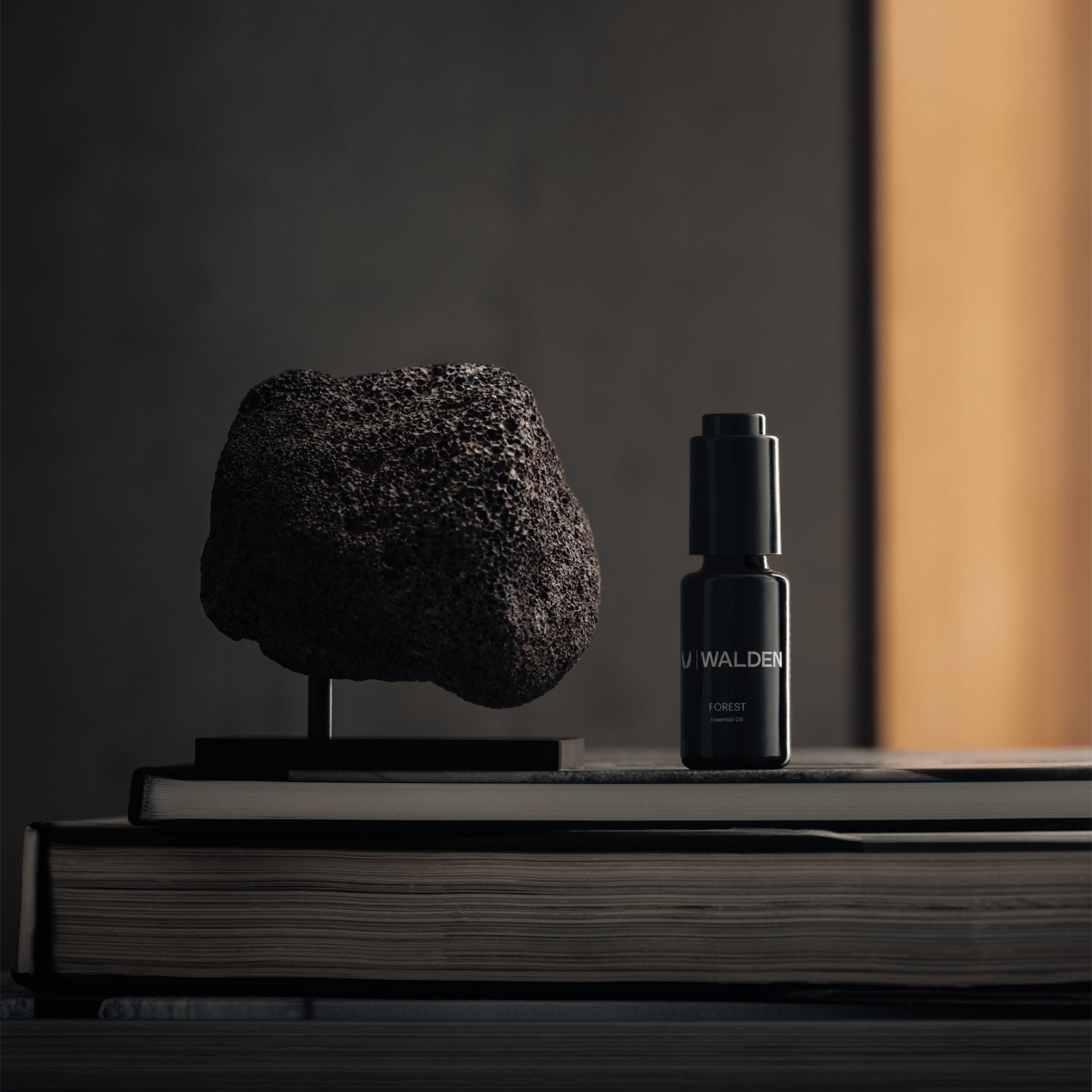 ASRV Walden Essential Oil Forest in black bottle with textured stone sculpture and books