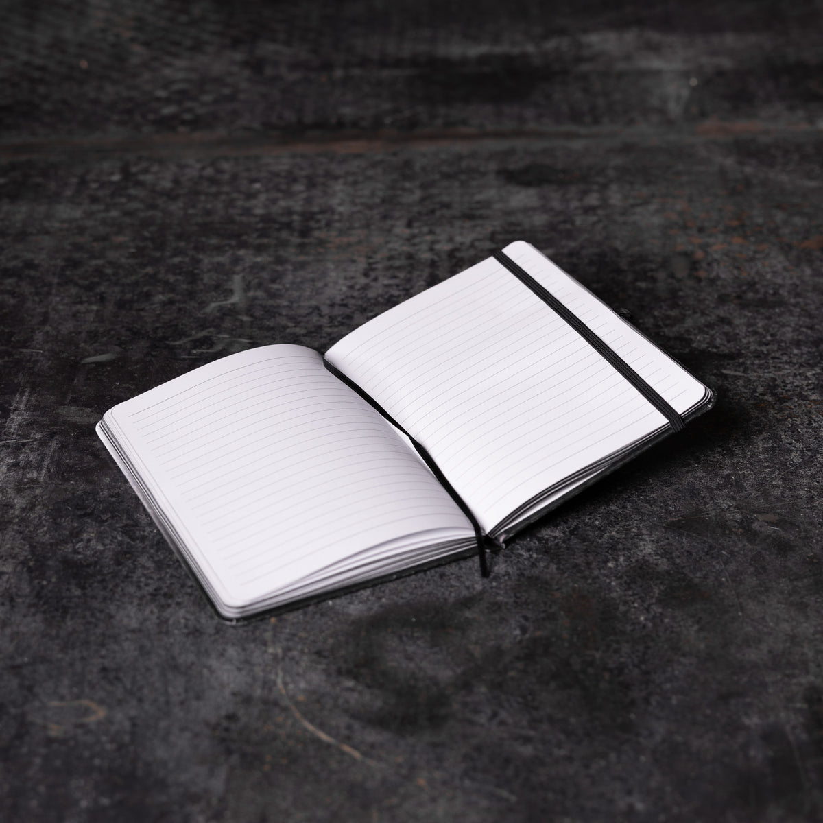 Flatlay of SM'22 OTWR Notebook in white and black, open pages view on dark textured surface