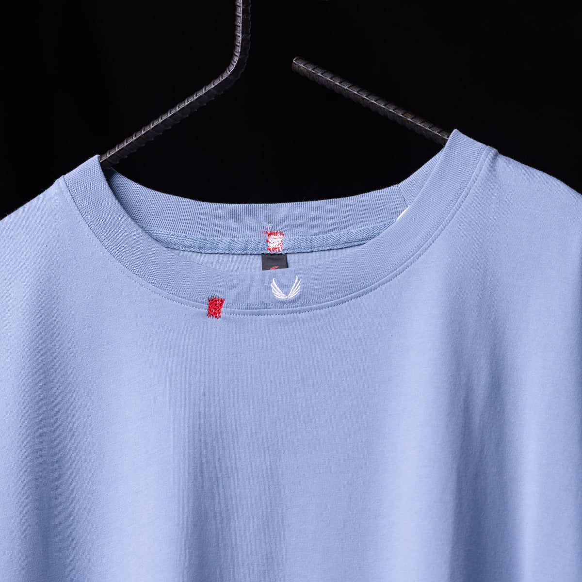 SM'22 Distressed Tee in periwinkle blue on hanger, front view showing neckline and label details