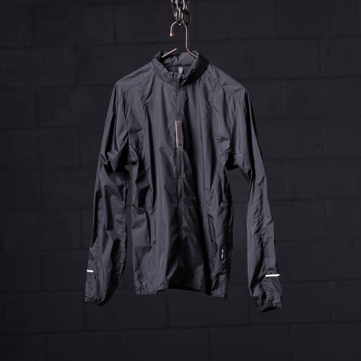 Black lightweight windbreaker displayed on hanger against dark background