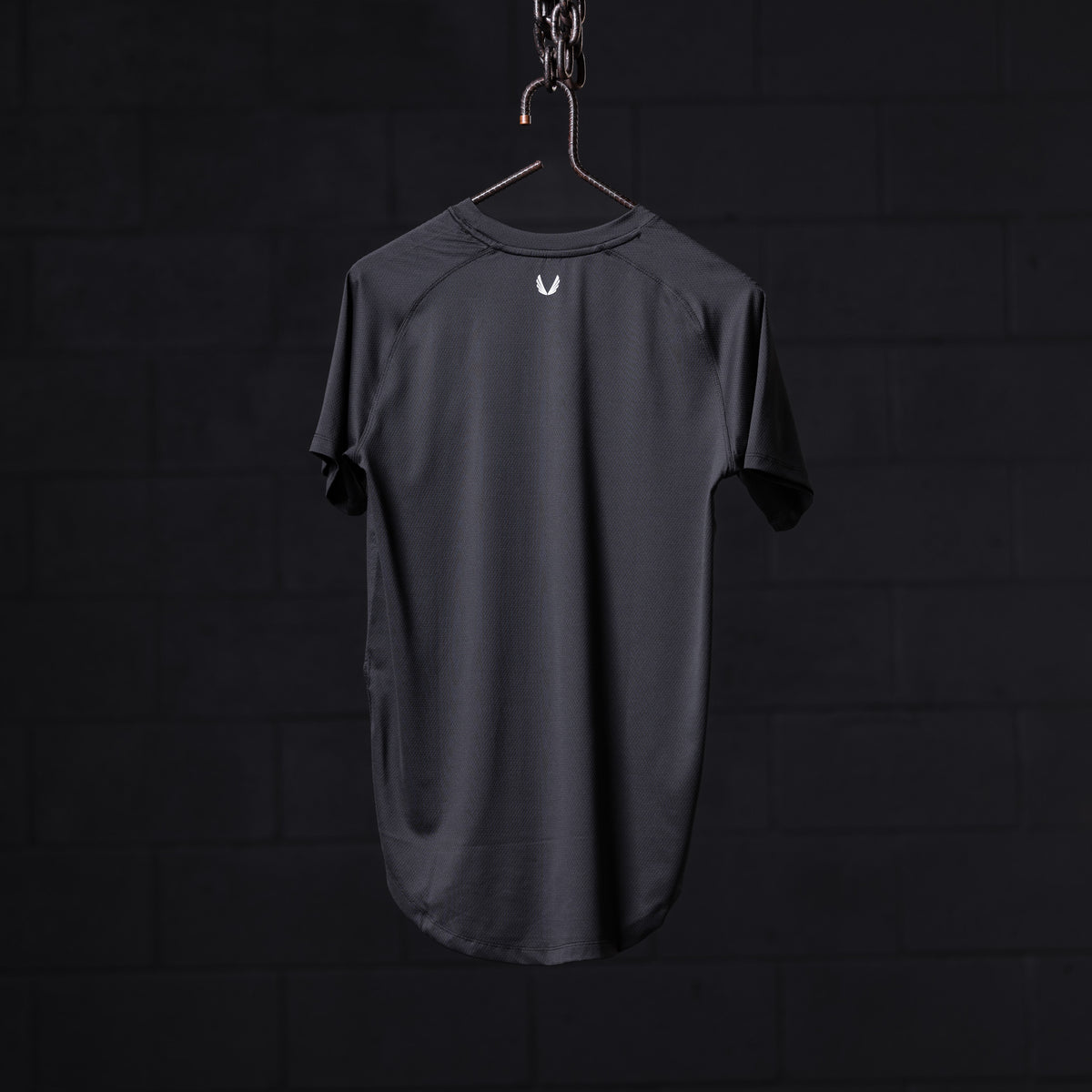 SM'22 Established Tee in charcoal gray, displayed on hanger against dark background, back view