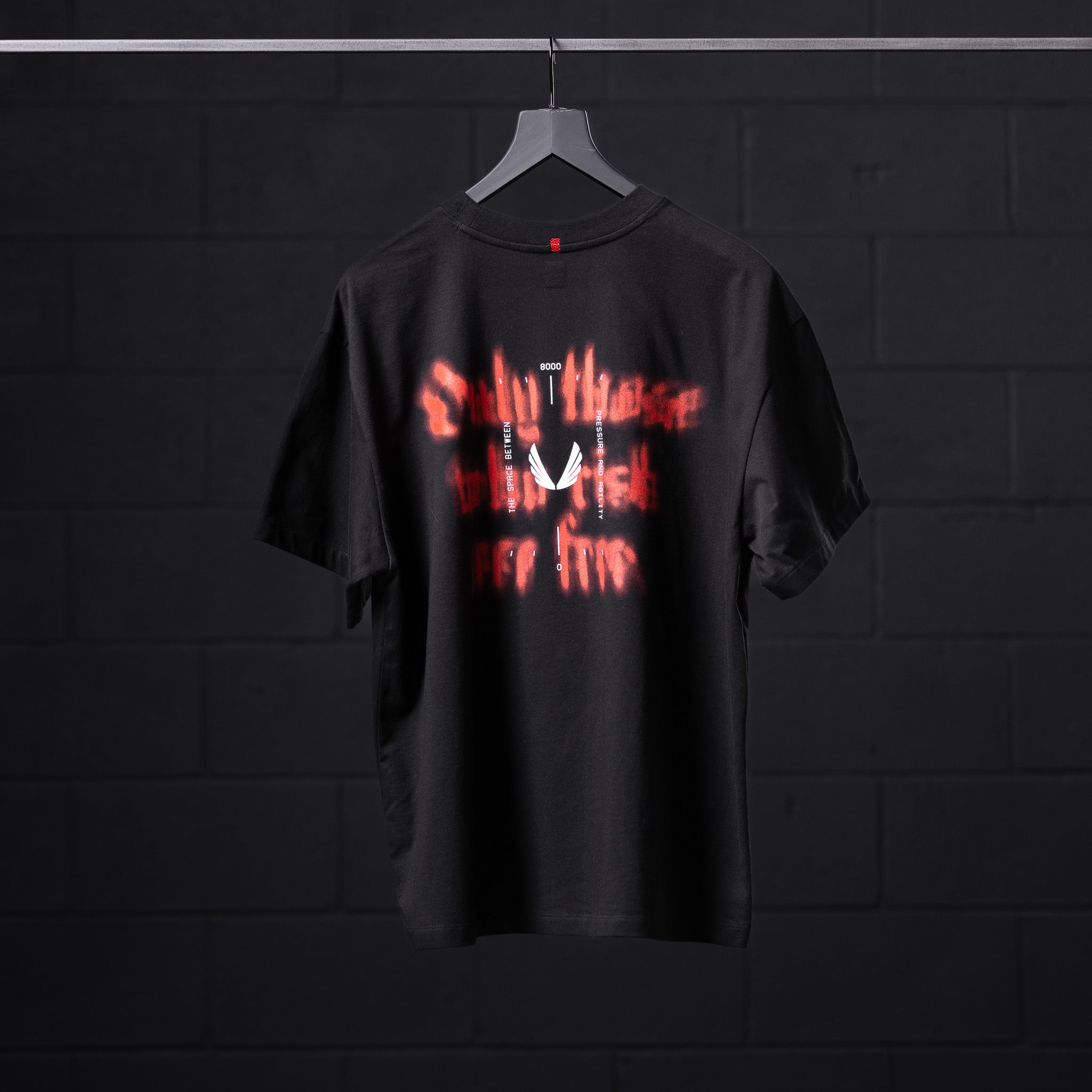 Black Tech Essential Relaxed Tee with red glowing graphic design, displayed on hanger back view
