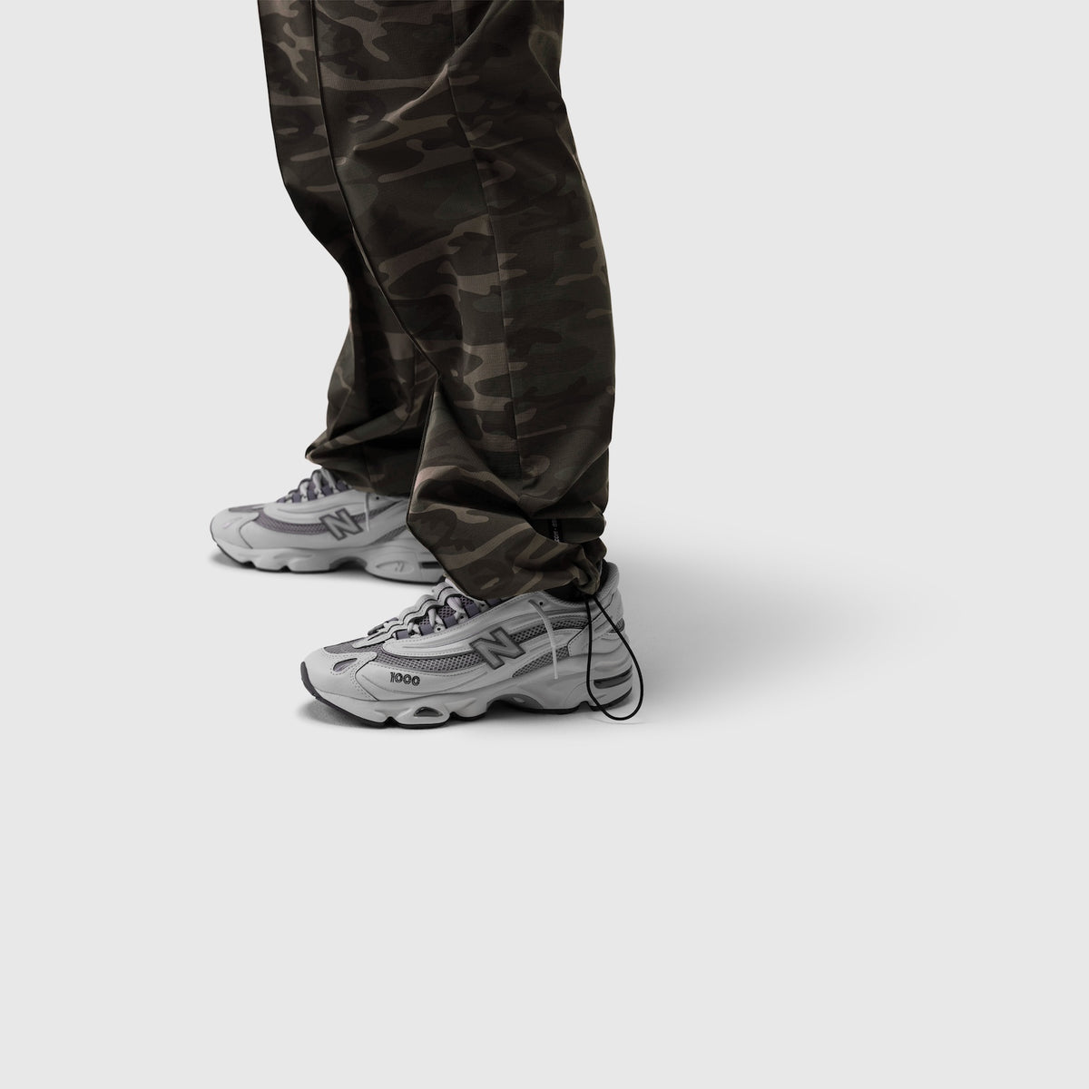 Dark camo ripstop relaxed track pant worn with white sneakers, front view