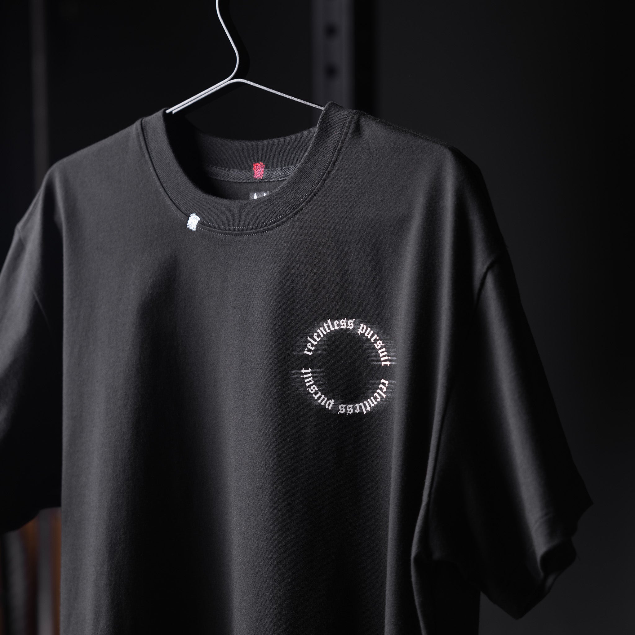 Black Tech Essential Relaxed Tee with circular 'RP Blur' logo on hanger, front view