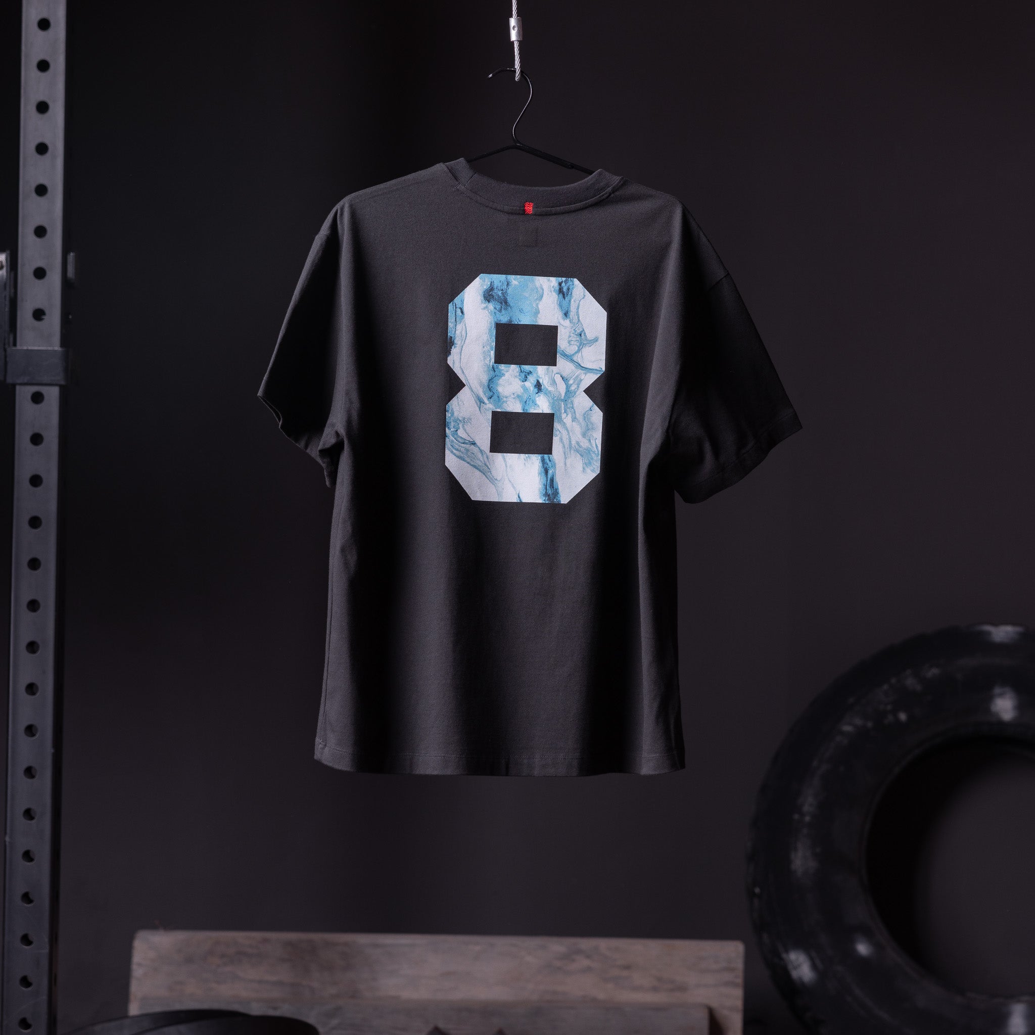 Black Tech Essential Relaxed Tee with blue marble number 8 graphic, back view on hanger
