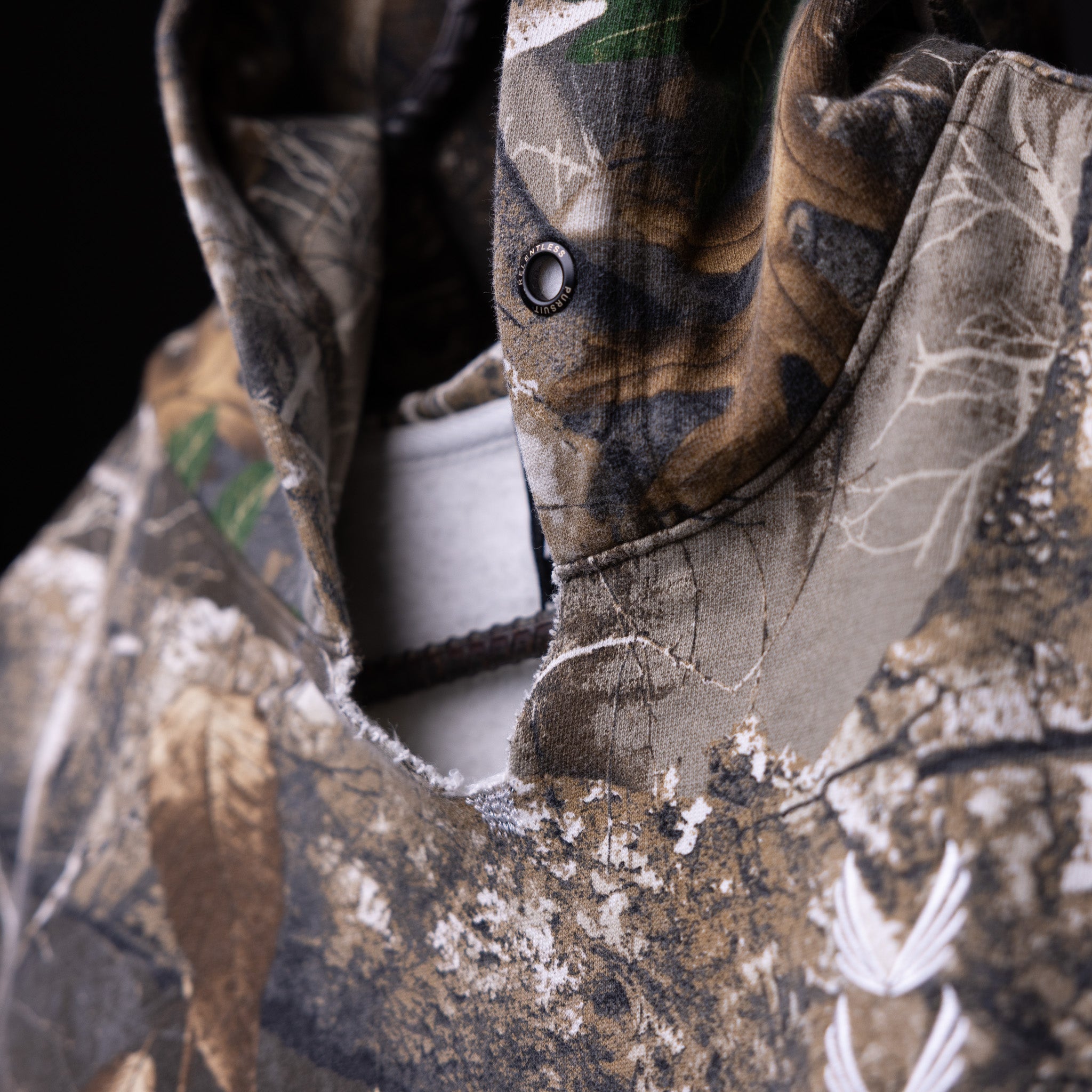 Raw Hem Cutoff Hoodie in grey camo, worn detail showing distressed fabric and grommet