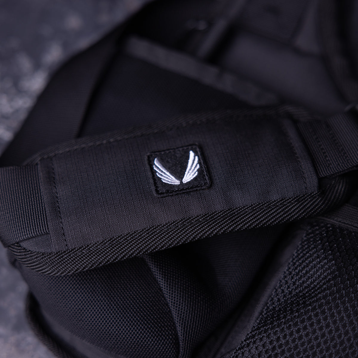 SM'23 Crossbody in black, close-up detail of logo patch