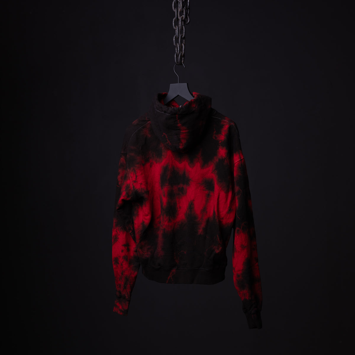 SM'22 Tie Dye Hoodie in red and black tie dye, displayed on hanger against dark background