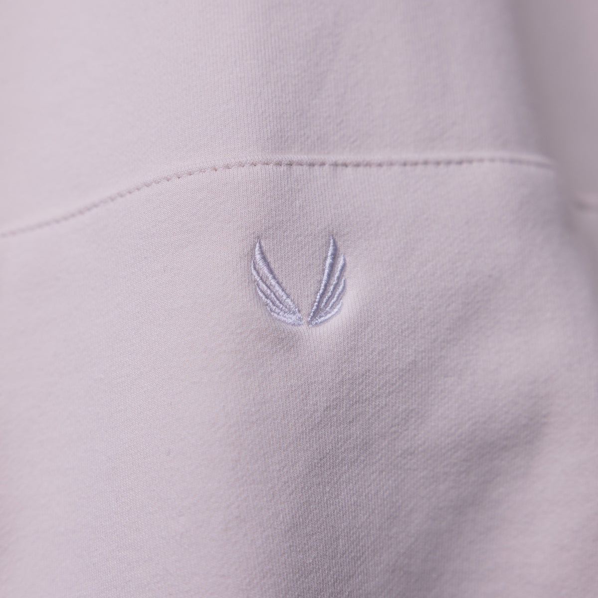 Tech Terry Eagle Hoodie detail closeup showing embroidered wing logo on light lavender fabric