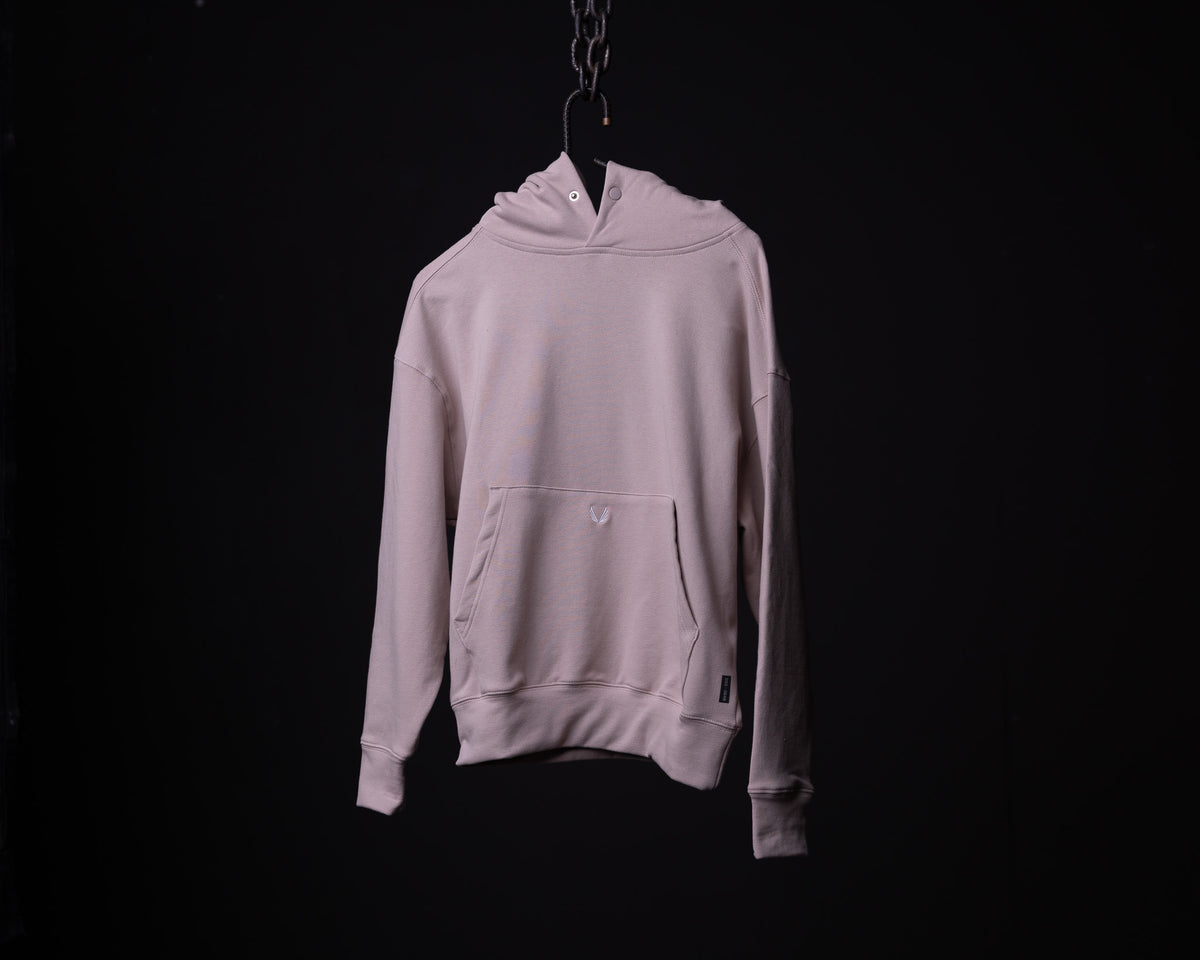 Light mauve Tech Terry Eagle Hoodie hanging on chain against black background