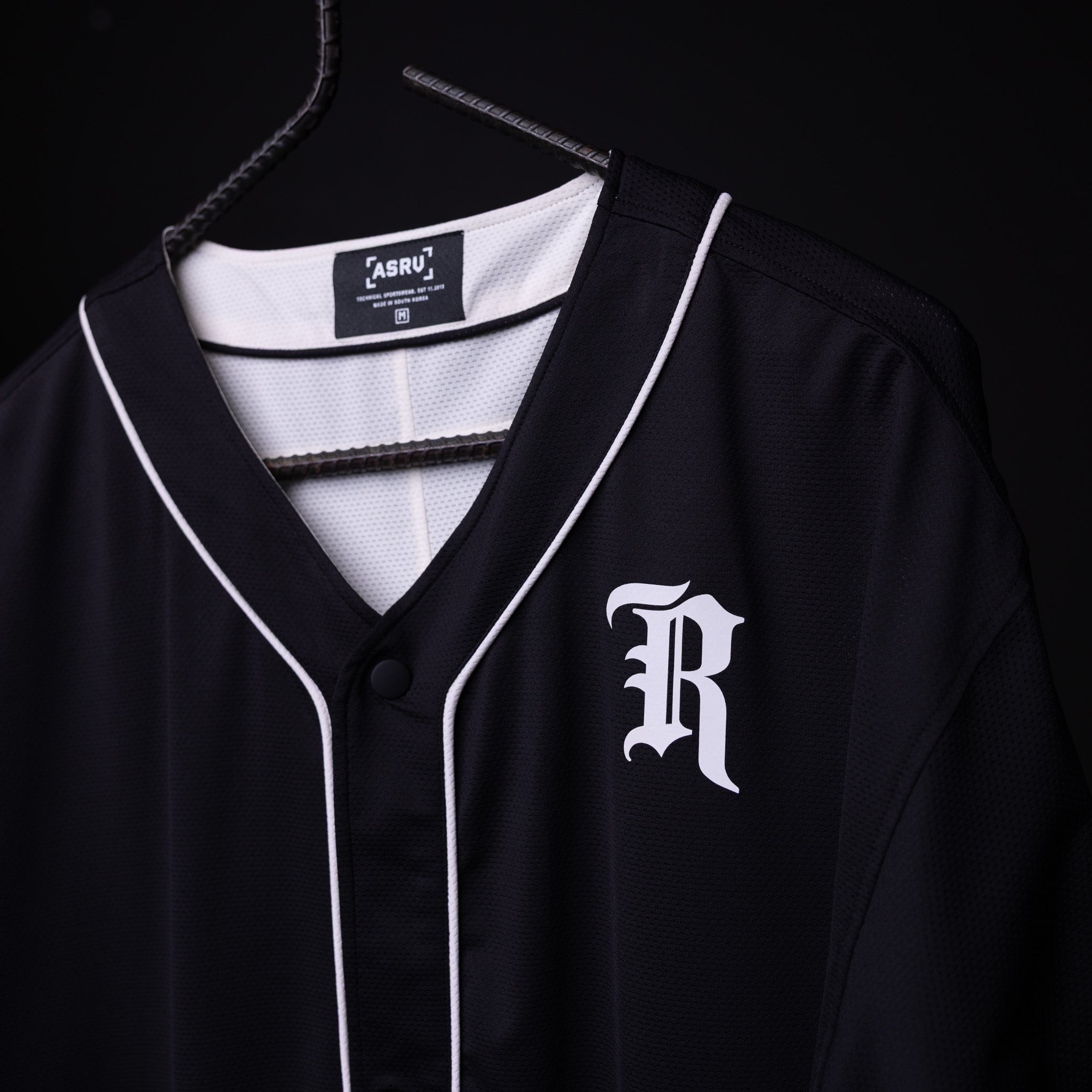 FA'21 Reversible Jersey in black with white piping on hanger, front view