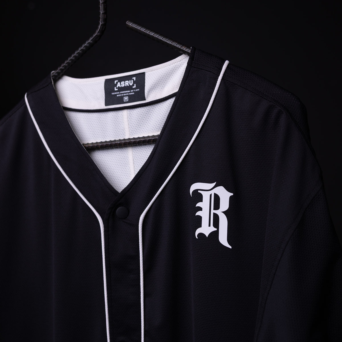 FA'21 Reversible Jersey in black with white piping on hanger, front view