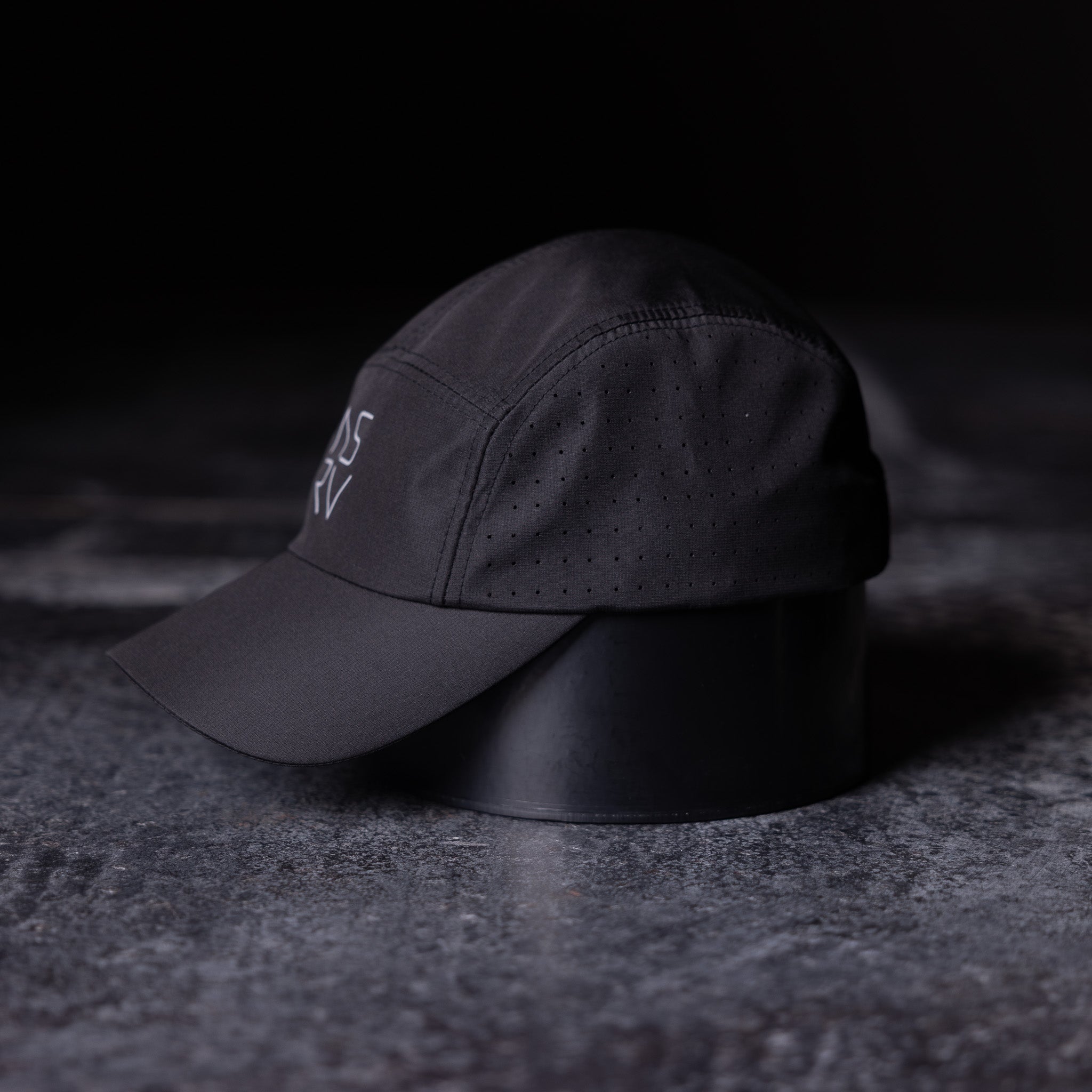 WN'22 Vented Hat in black, side angle view on textured surface