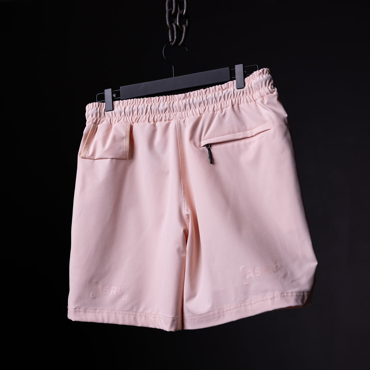 of pink Coastal Training Short on black hanger against dark background, back view