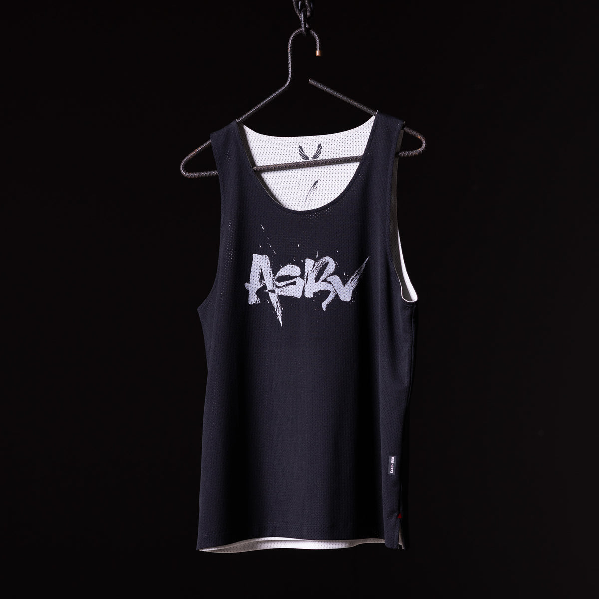 SM'23 Mesh Reversible Pinnie in black with white mesh lining, displayed on hanger