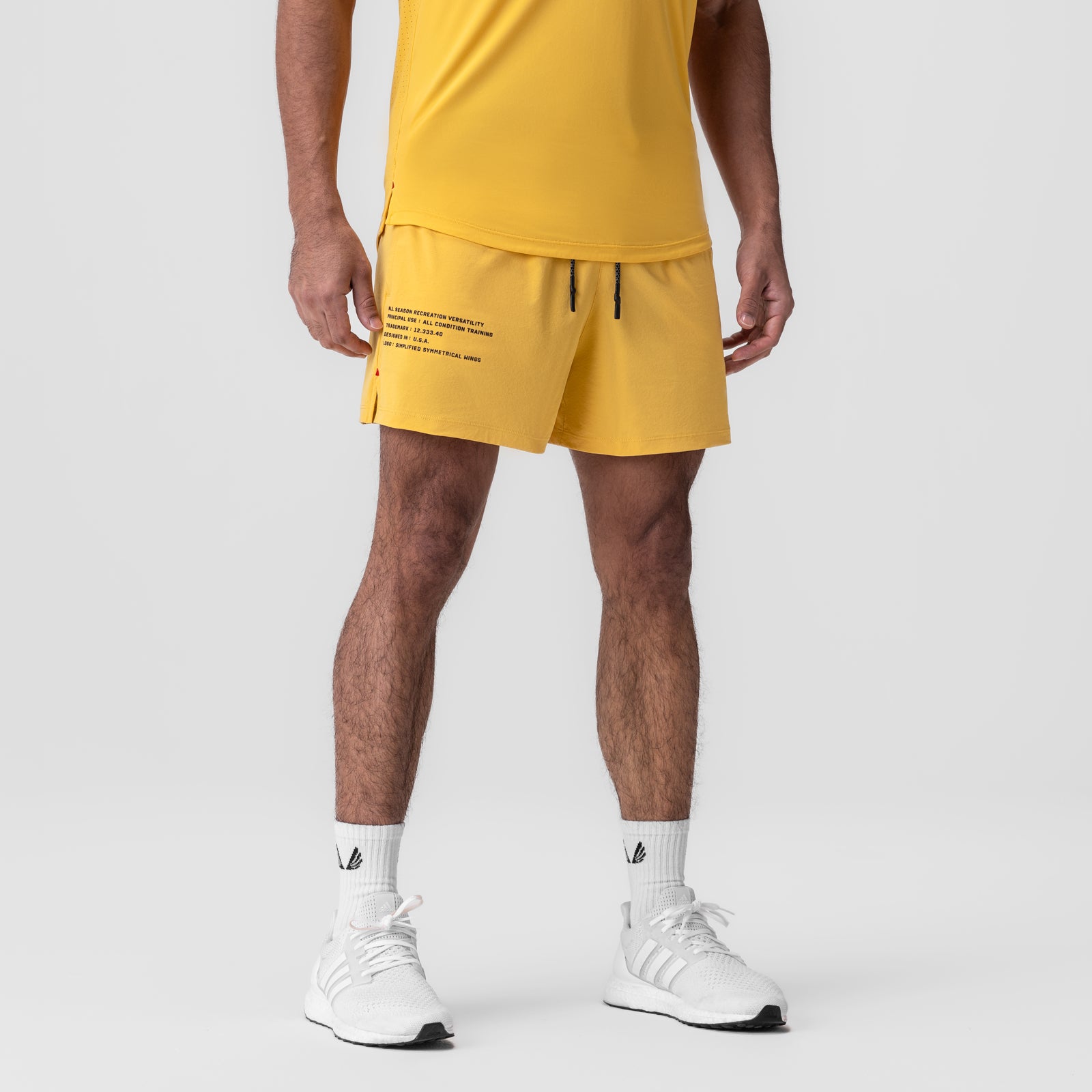 Aerotex Training Short in amber yellow worn with white socks and sneakers, front view