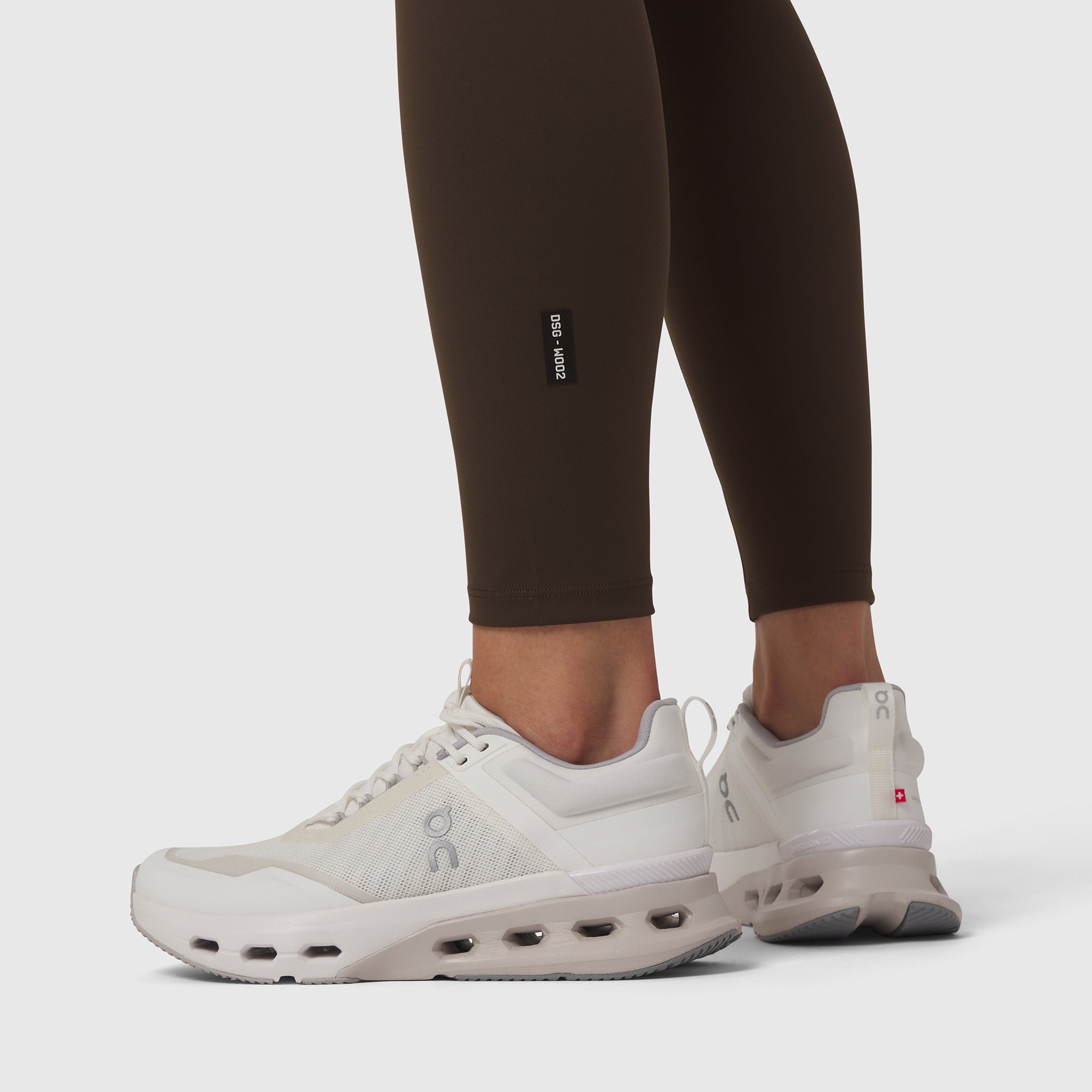 W002 LYCRA® ADAPTIV Legging in Dark Earth, worn with white sneakers, side view