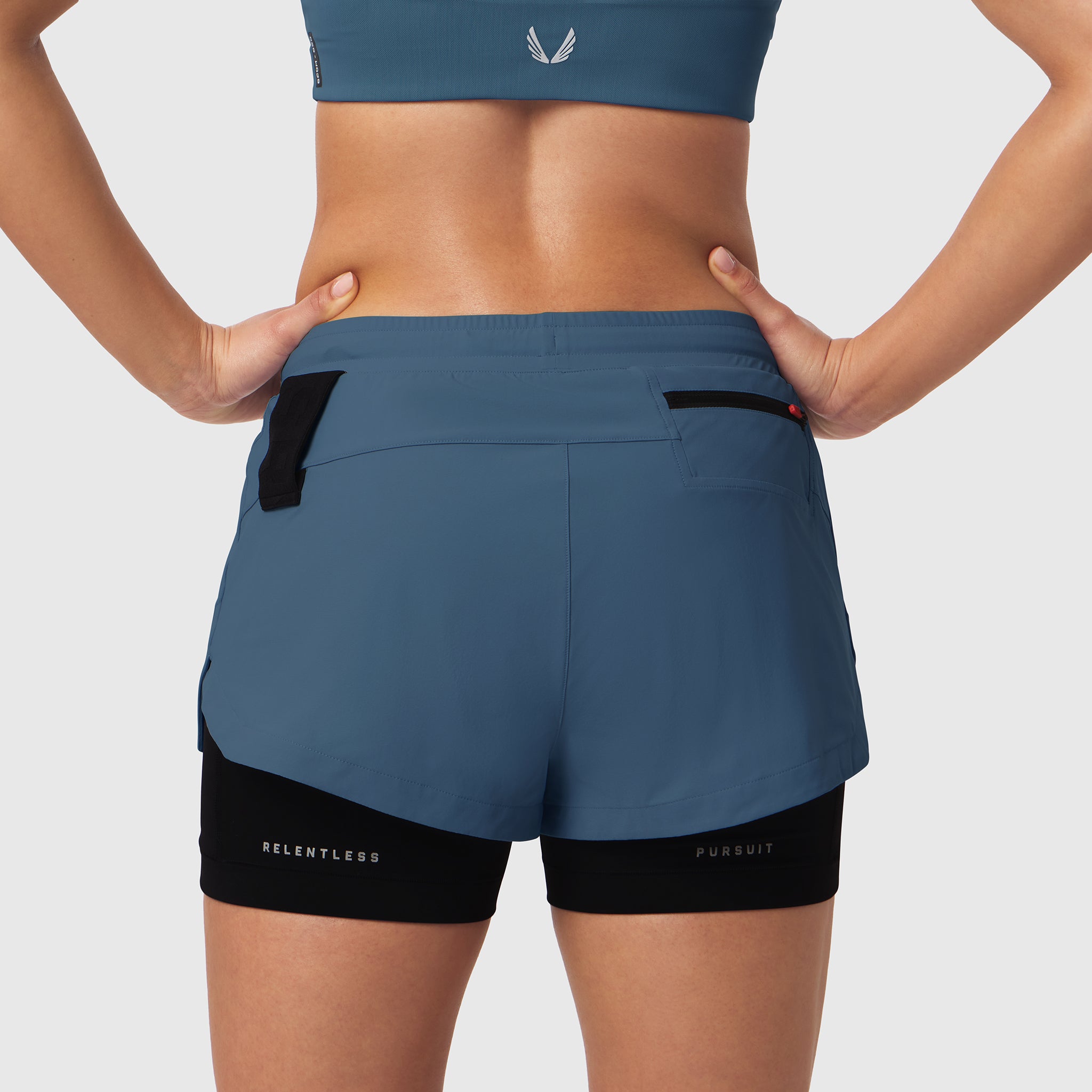 W025 Tetra-Lite Liner Short in storm blue, back view on model with hands on hips