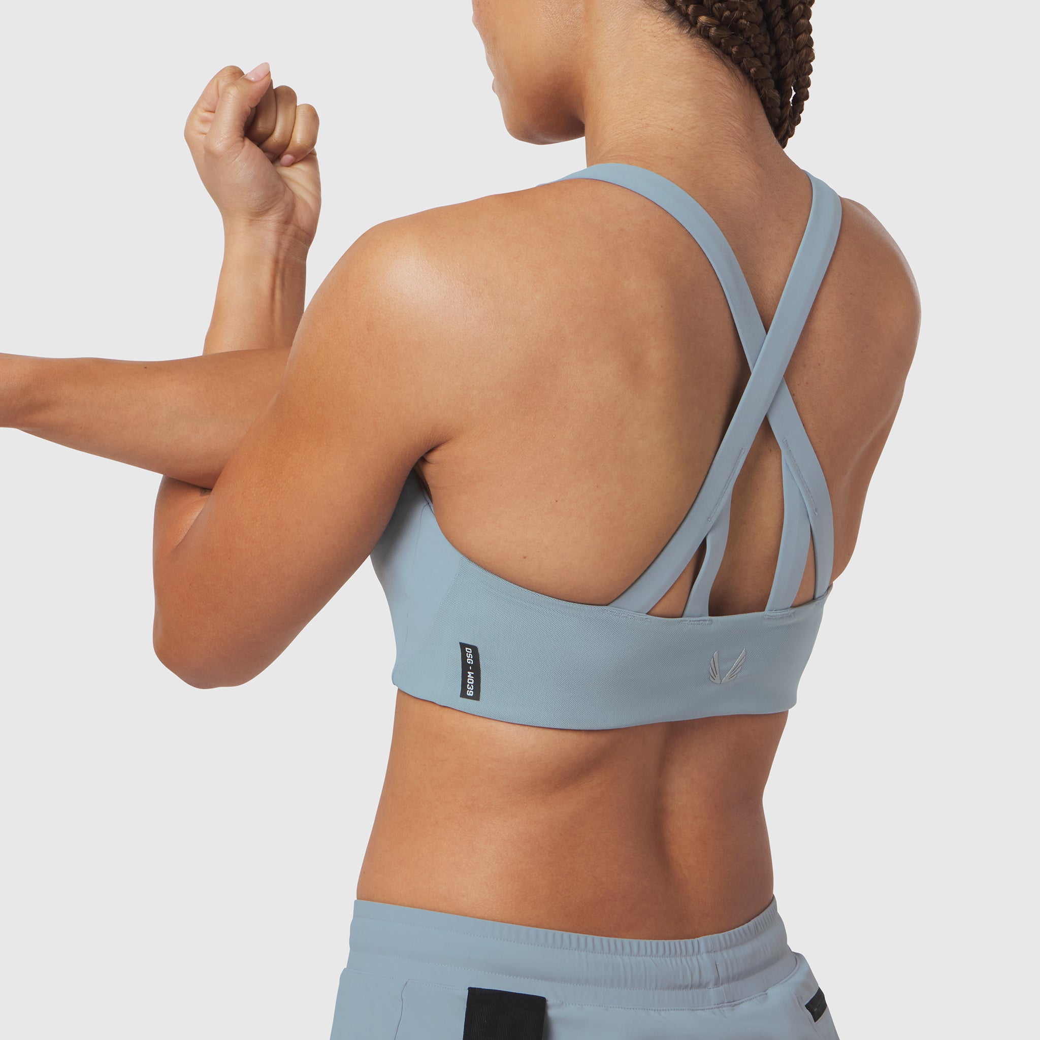 LYCRA® Hybrid Sports Bra in light sky, back view on model with arms raised