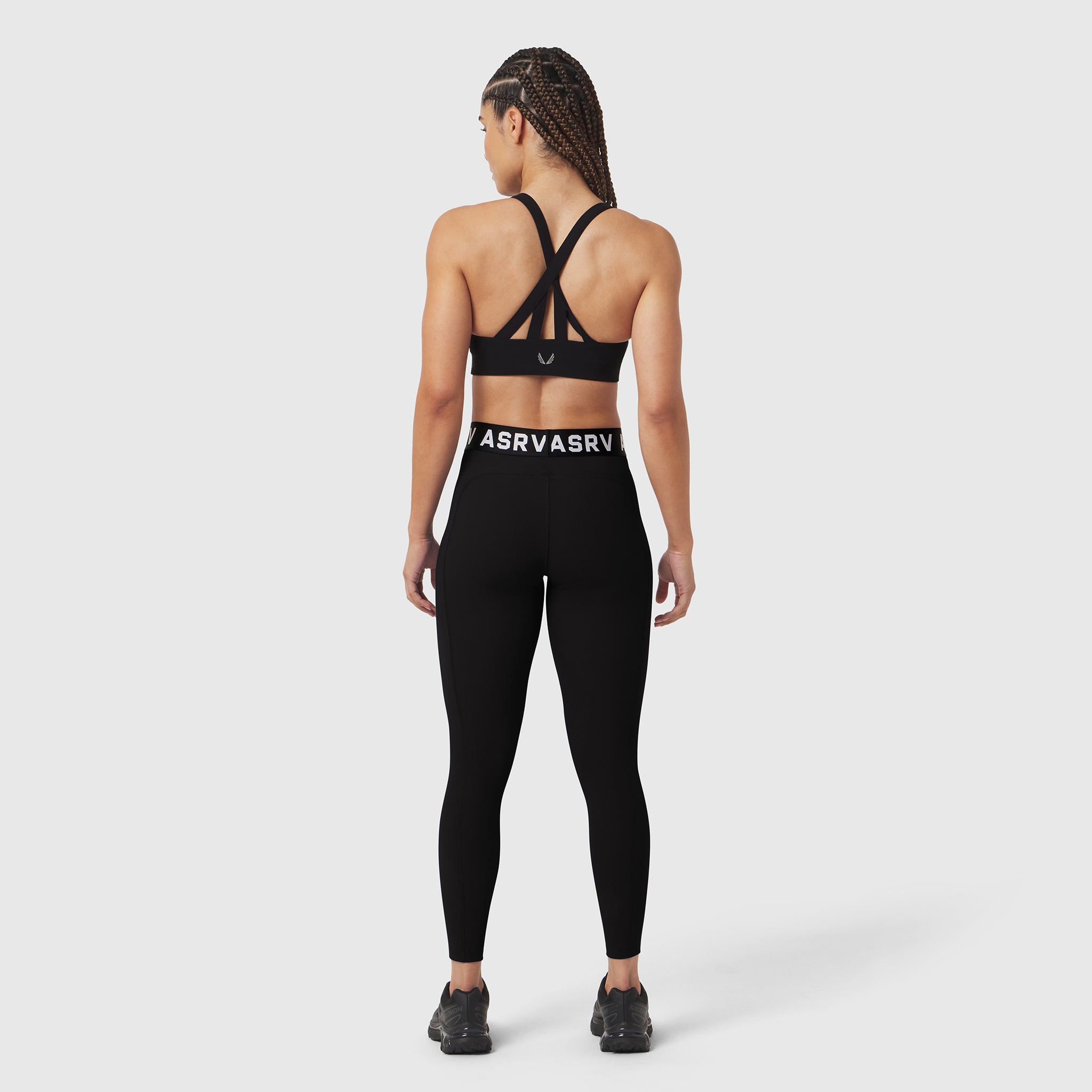 Black LYCRA® ribbed legging worn by model, back view, showing strappy sports bra