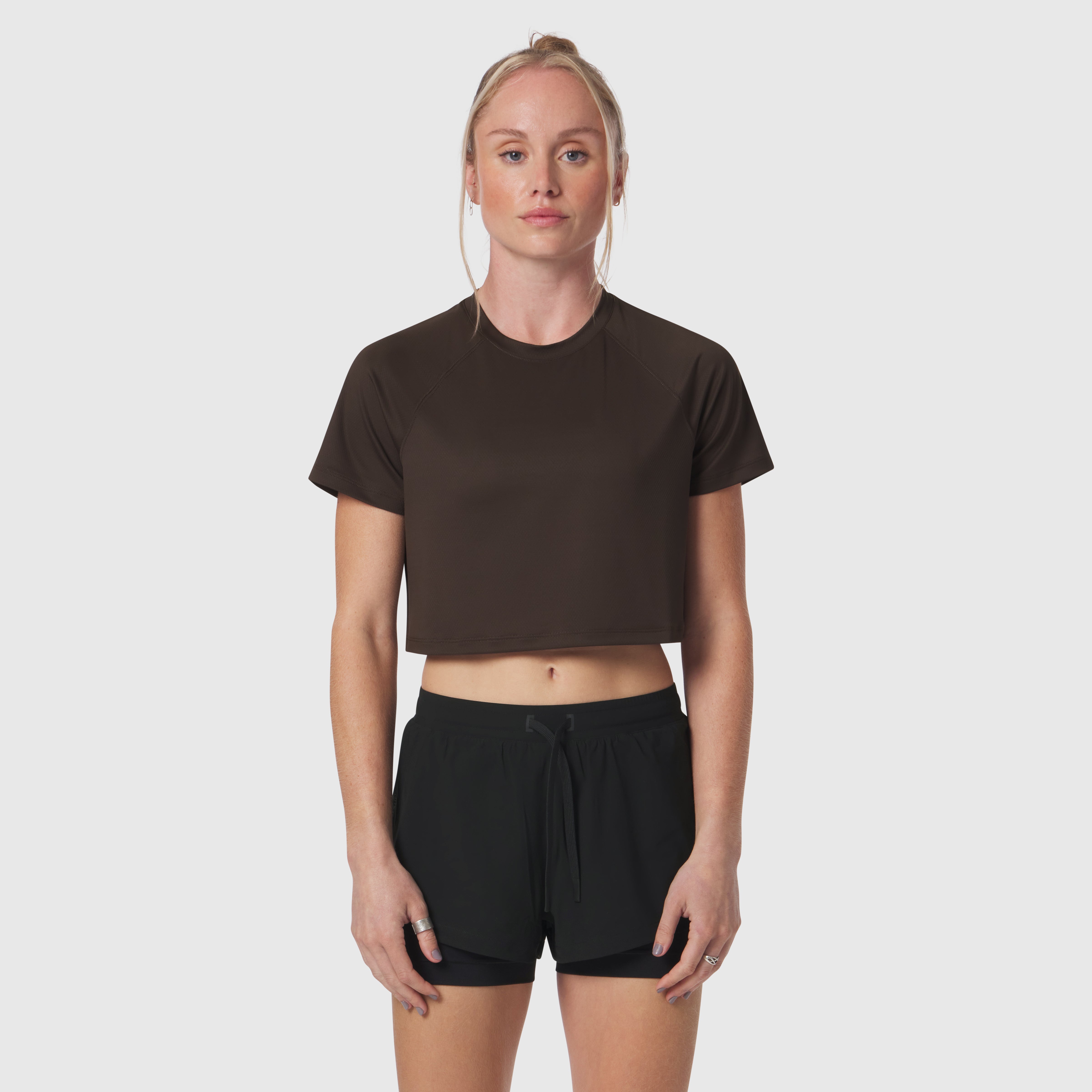 AeroSilver® cropped tee in dark earth, worn with black shorts, front view on model