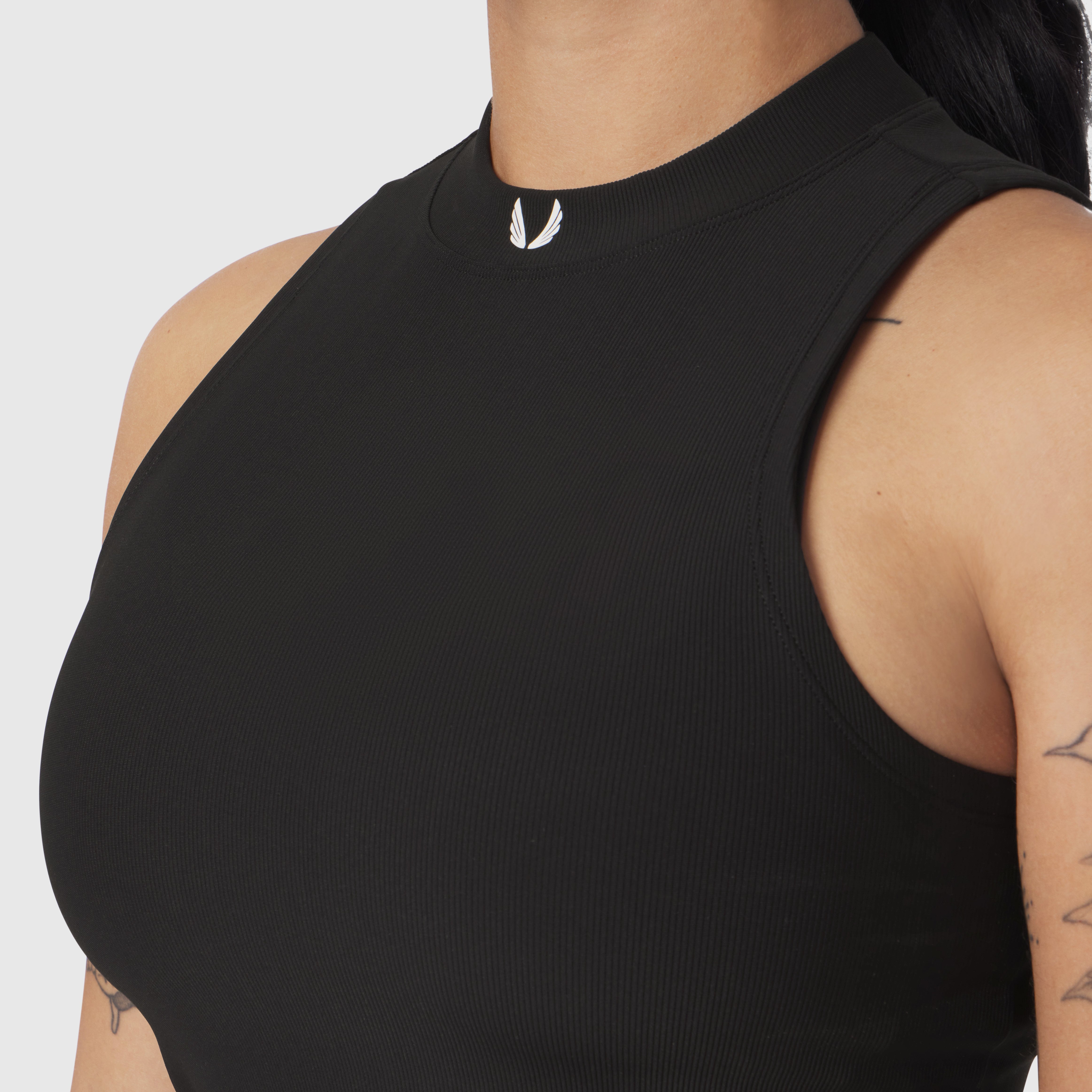 Black ribbed mockneck tank top worn by model, side view showing fit and fabric texture