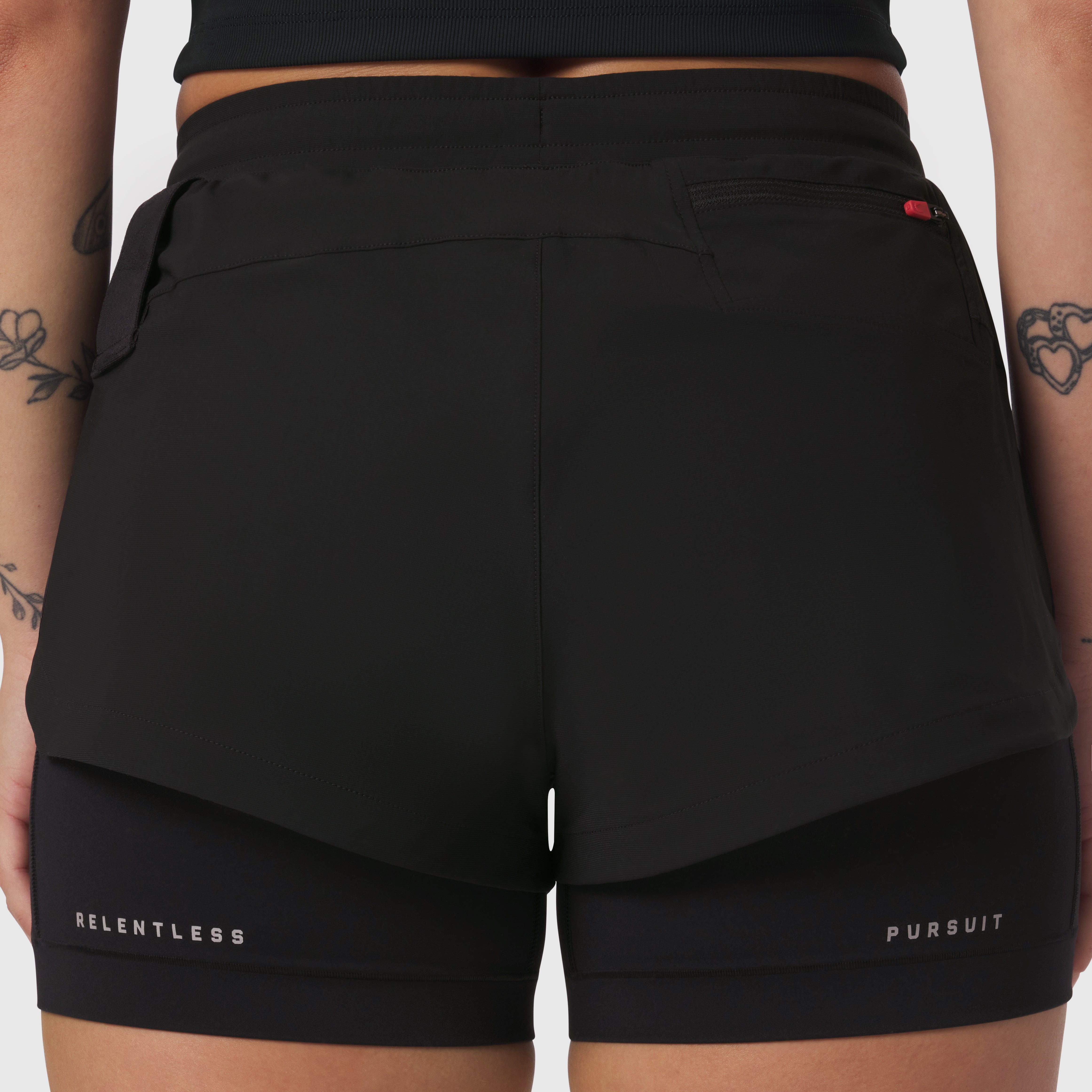 W025 Tetra-Lite Liner Short in black worn by model, back view showing 'Relentless Pursuit' text