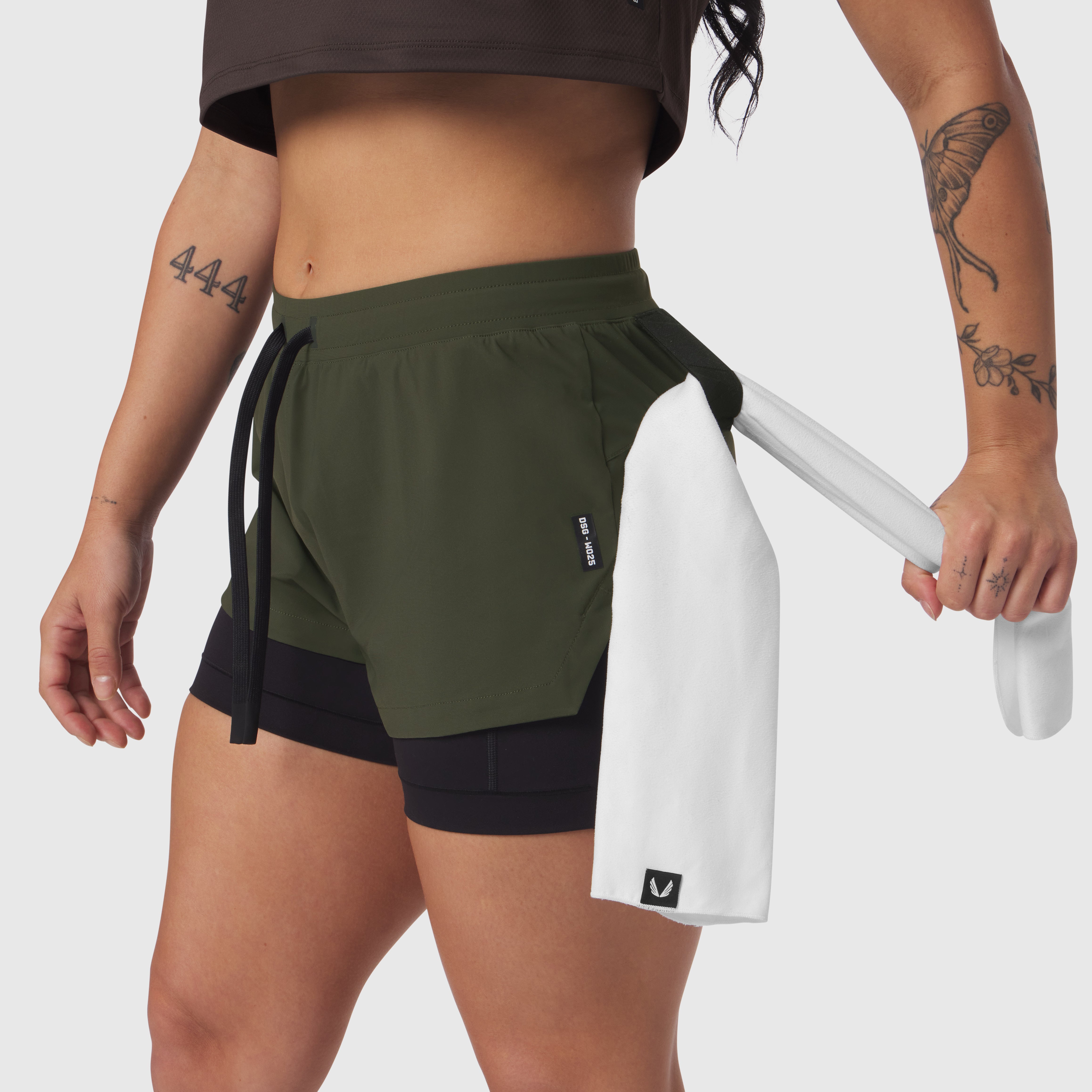 Tetra-Lite Liner Short in olive worn by model, holding white shorts, side view