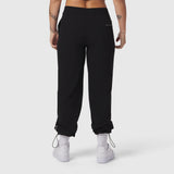 Black ripstop relaxed track pant worn by model, back view with cuffed ankles and white sneakers