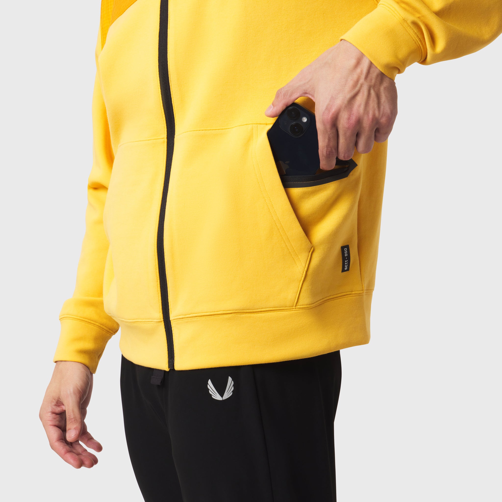 Dri-Core Sidelock Full Zip hoodie in amber yellow, worn by model holding phone in pocket