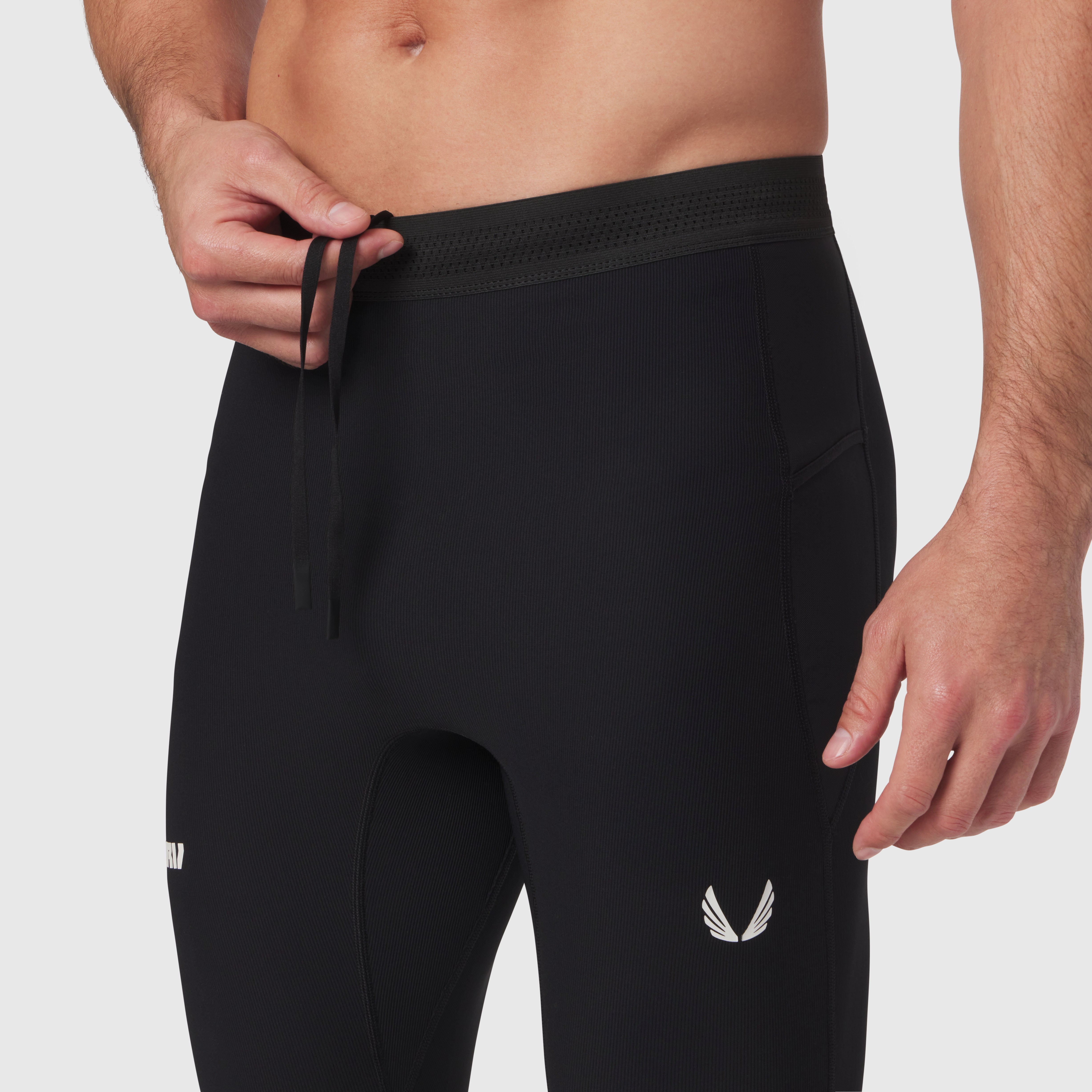 Black Lycra ribbed running tight worn by male model, waistband detail with drawstring visible