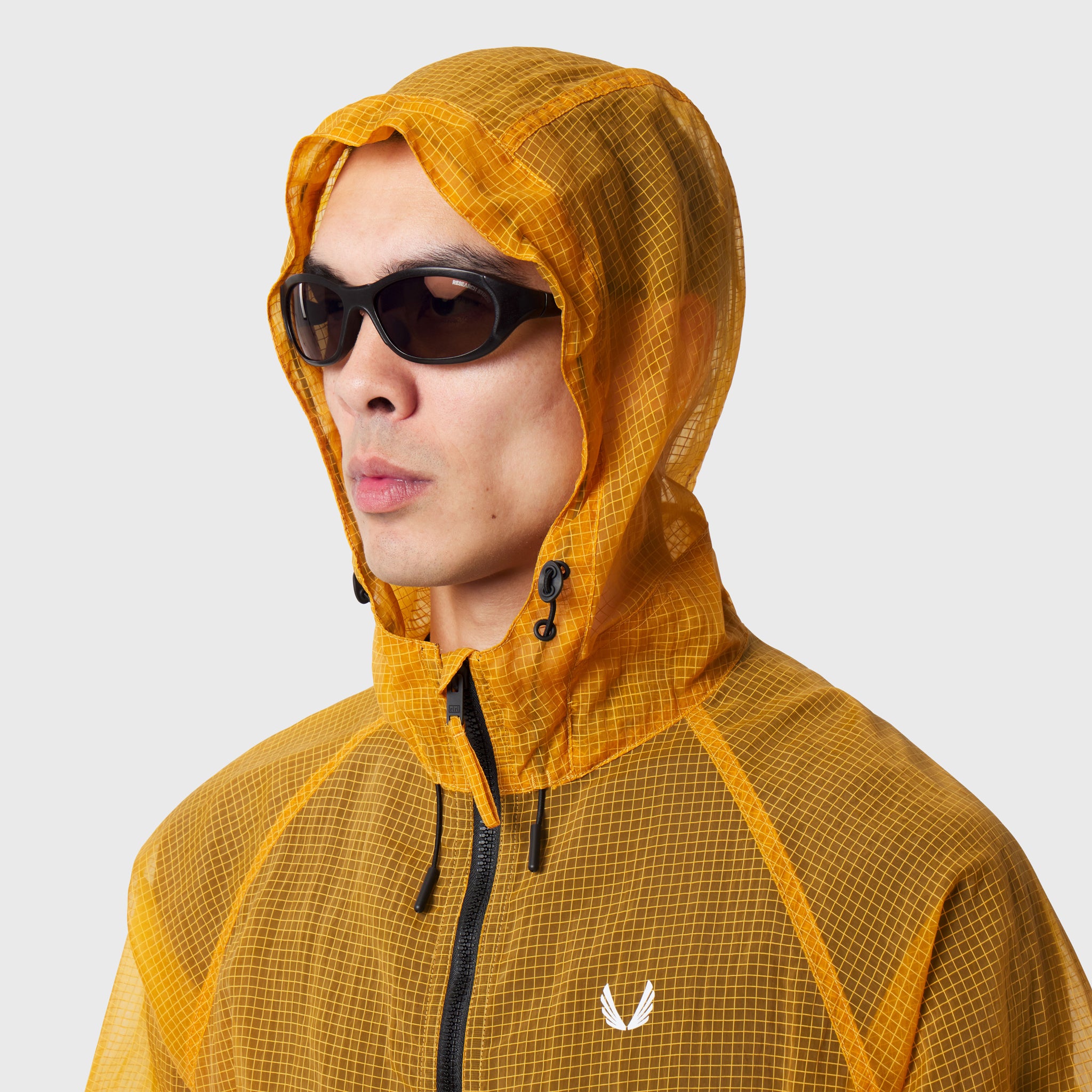 Weather-Ready Transparent Ripstop Shell Jacket in amber, modeled with hood up and sunglasses