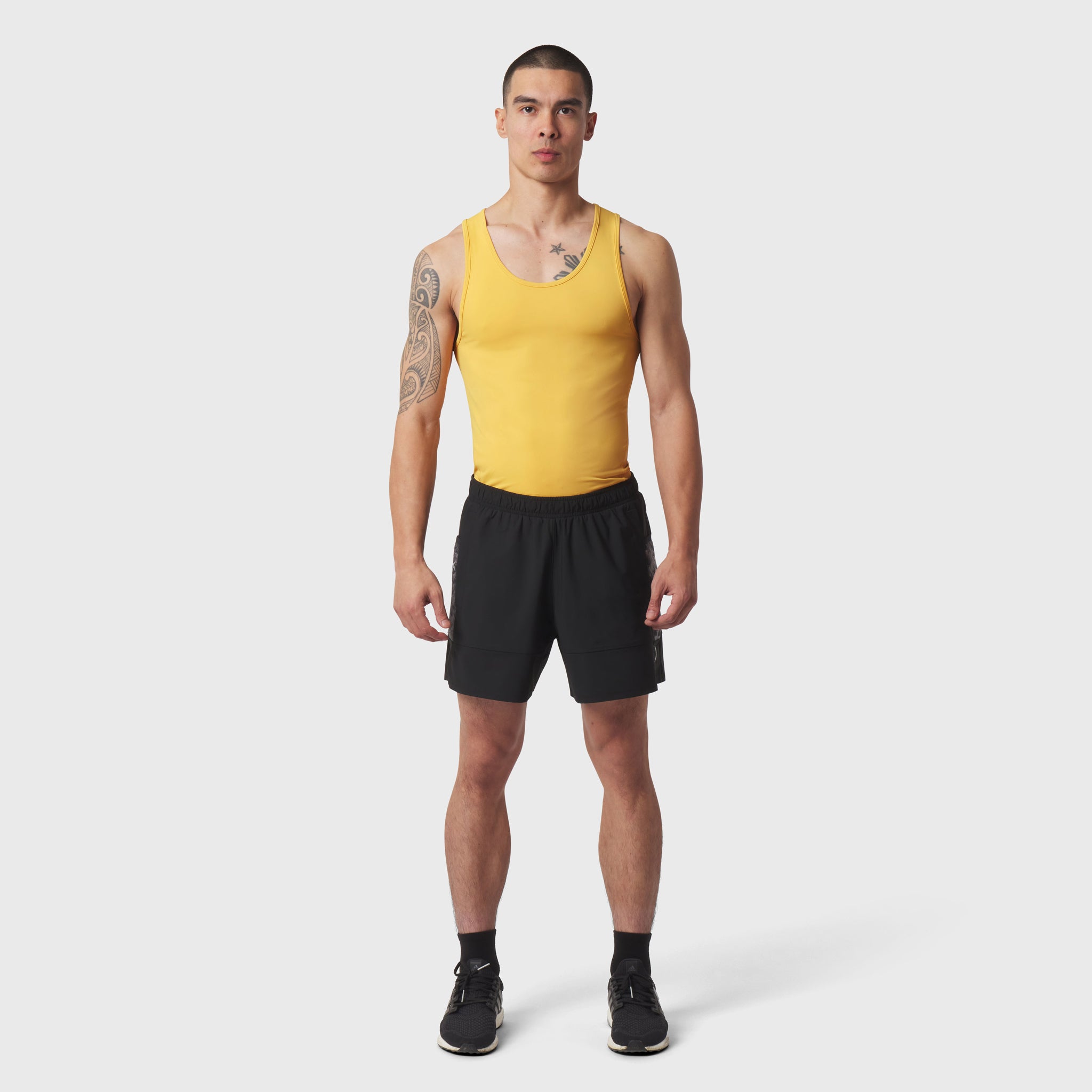 LYCRA® ADAPTIV Baselayer Tank in amber yellow worn with black shorts, front view