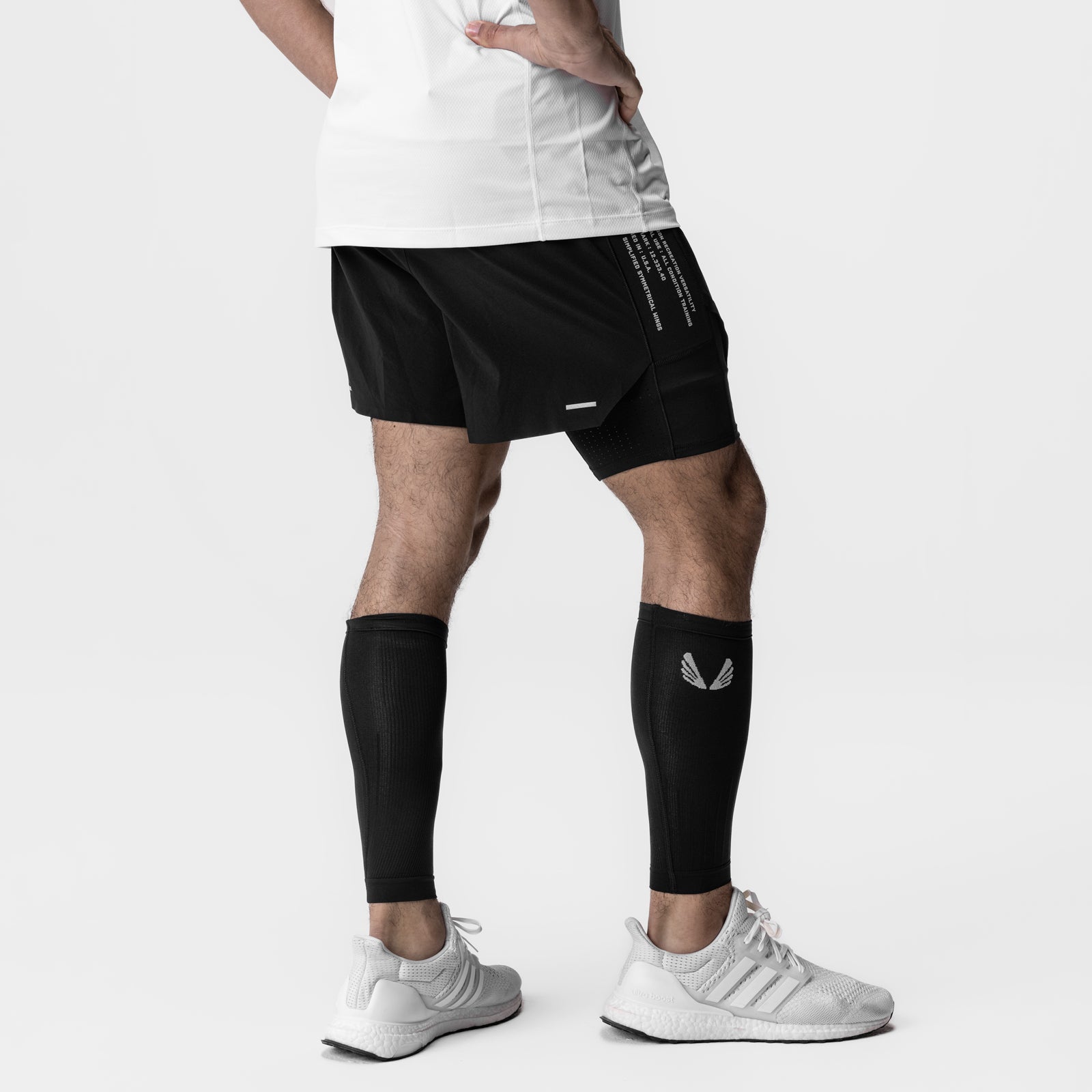Body-Mapped Calf Sleeve in black worn on model's legs with white sneakers and black shorts