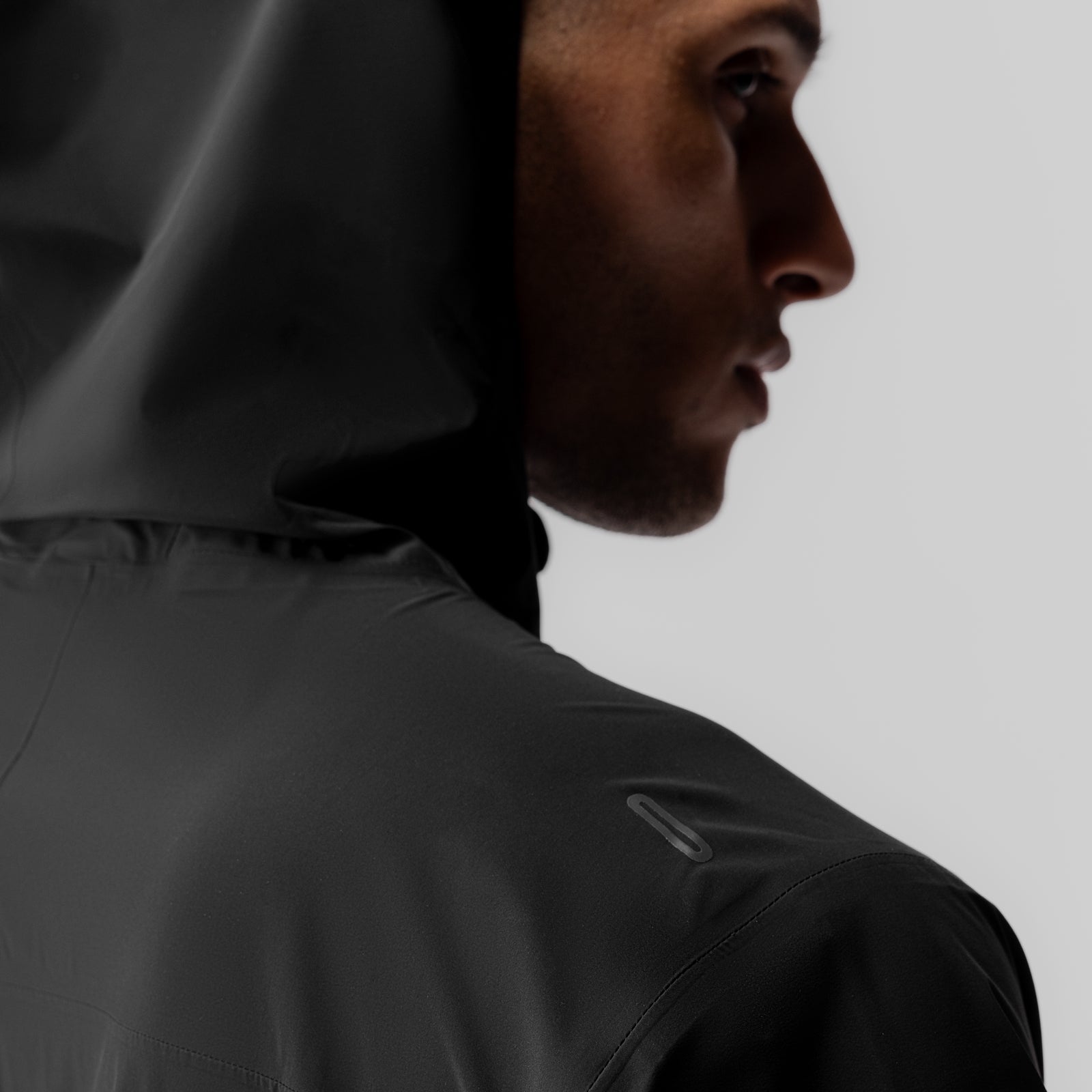Aerotex Lightweight Windbreaker in black, modeled in profile view with hood up